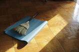 A straw broom resting on a blue yoga mat on a wooden floor