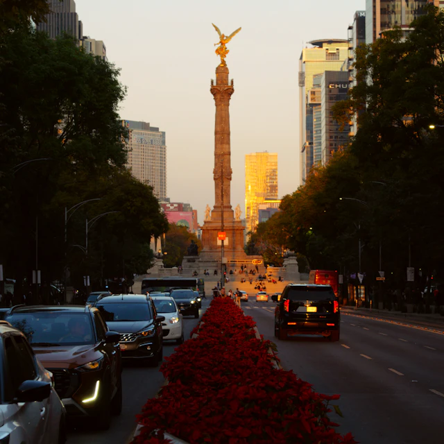 The Angel of Independence monument in Mexico City with traffic on a tree-lined avenue