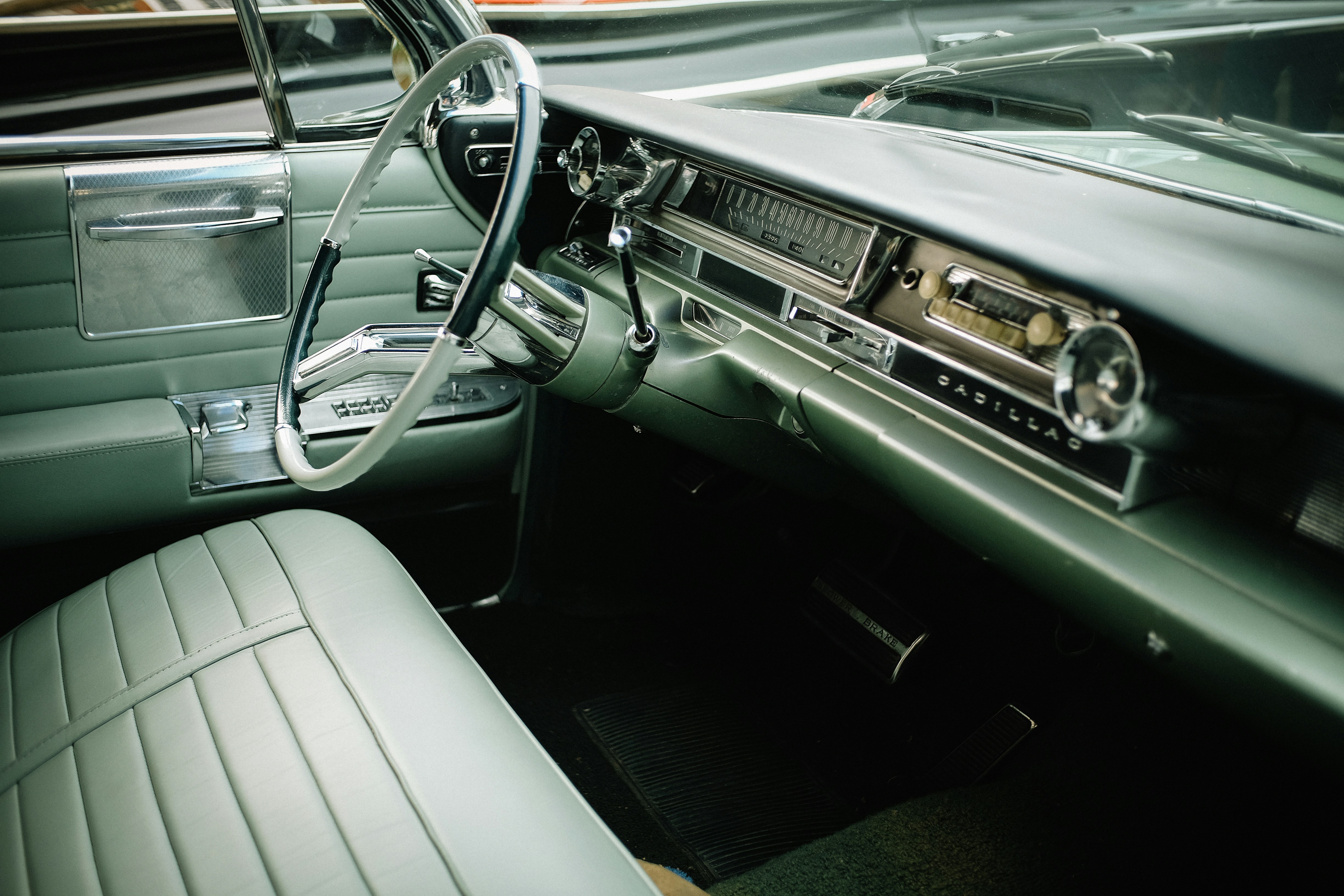The interior of a vintage Cadillac with green leather seats and a steering wheel - 相关推荐