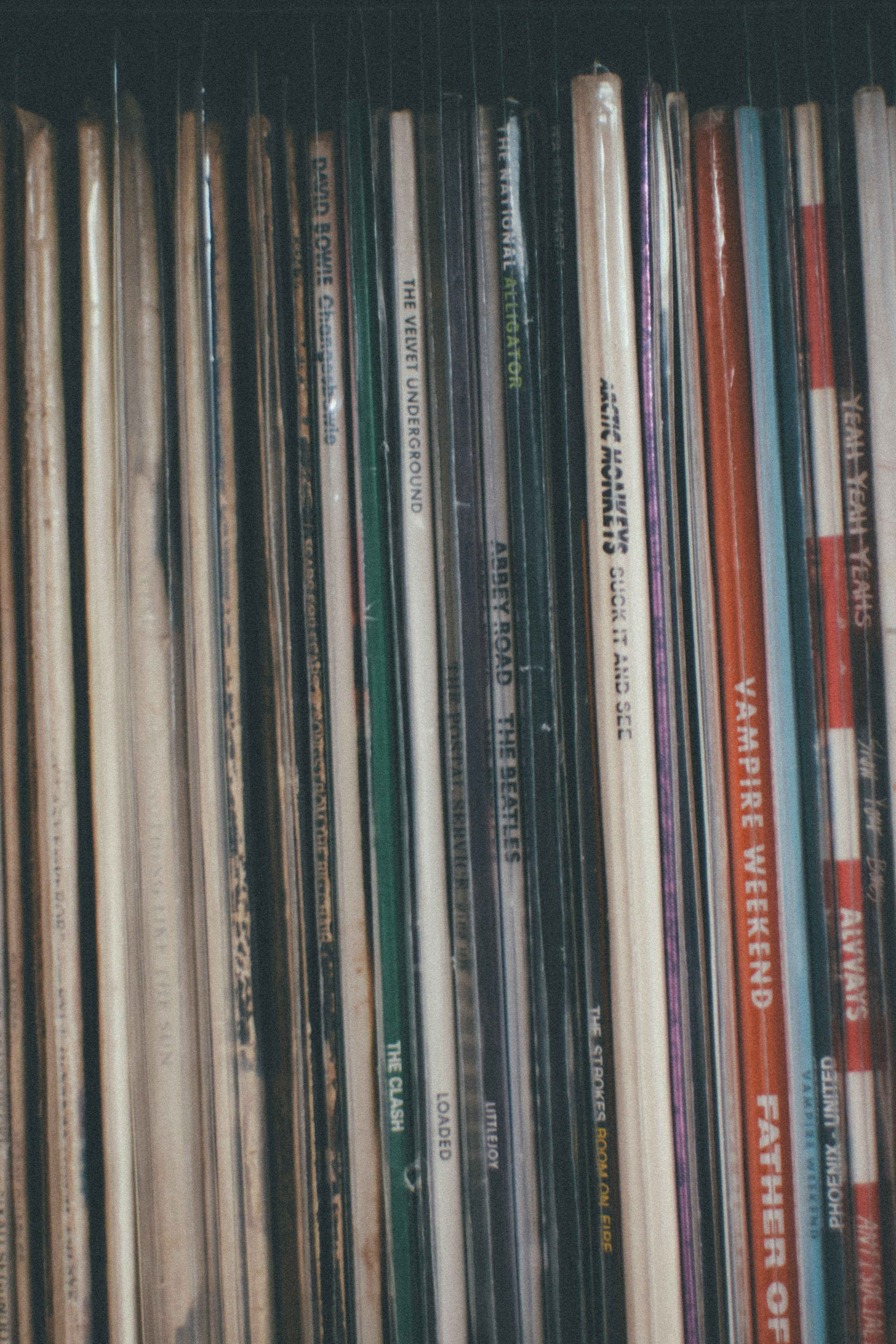 Uma fileira de capas de discos de vinil em pé em uma prateleira