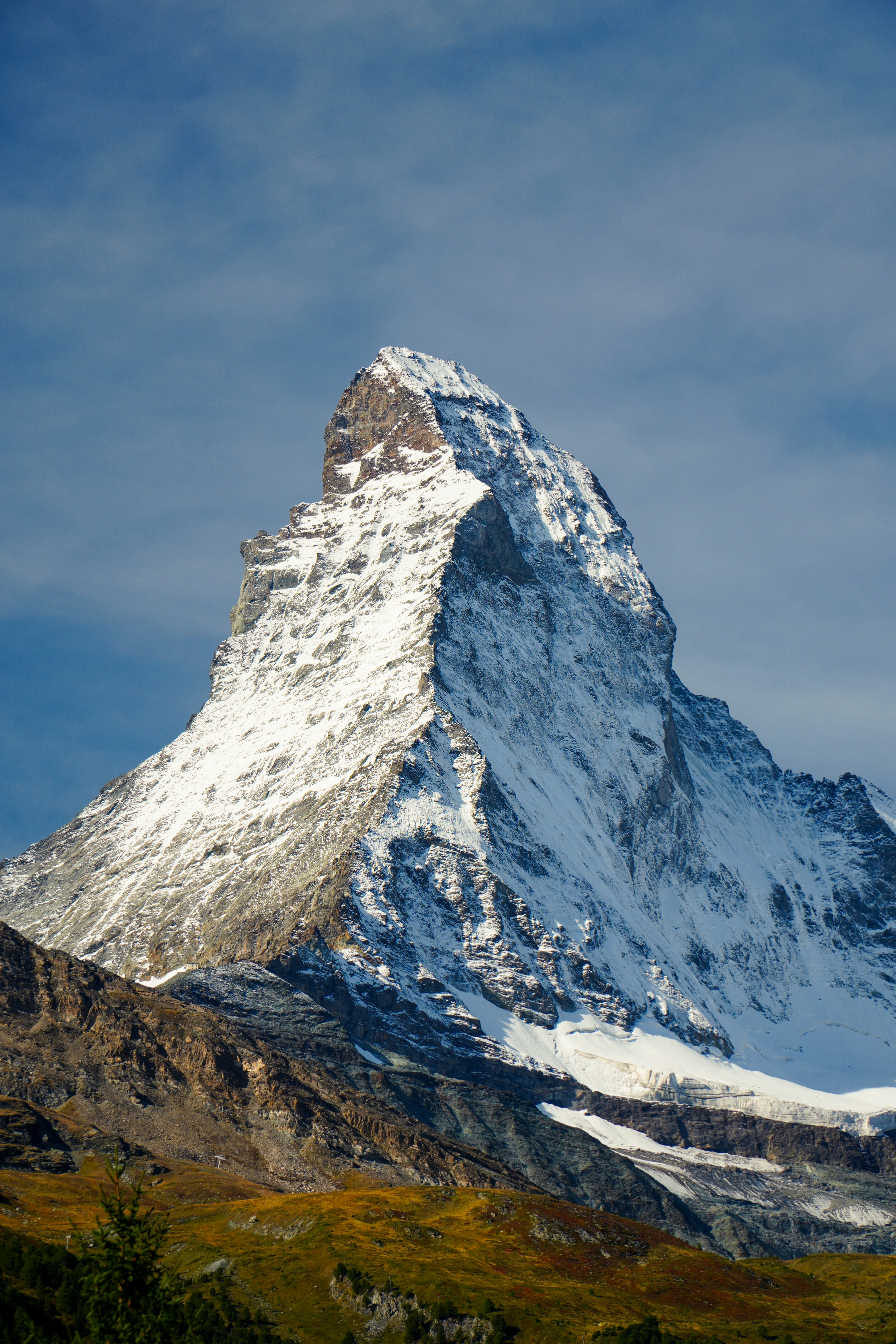 The Matterhorn peak with snow-covered slopes rising above a rocky mountain base