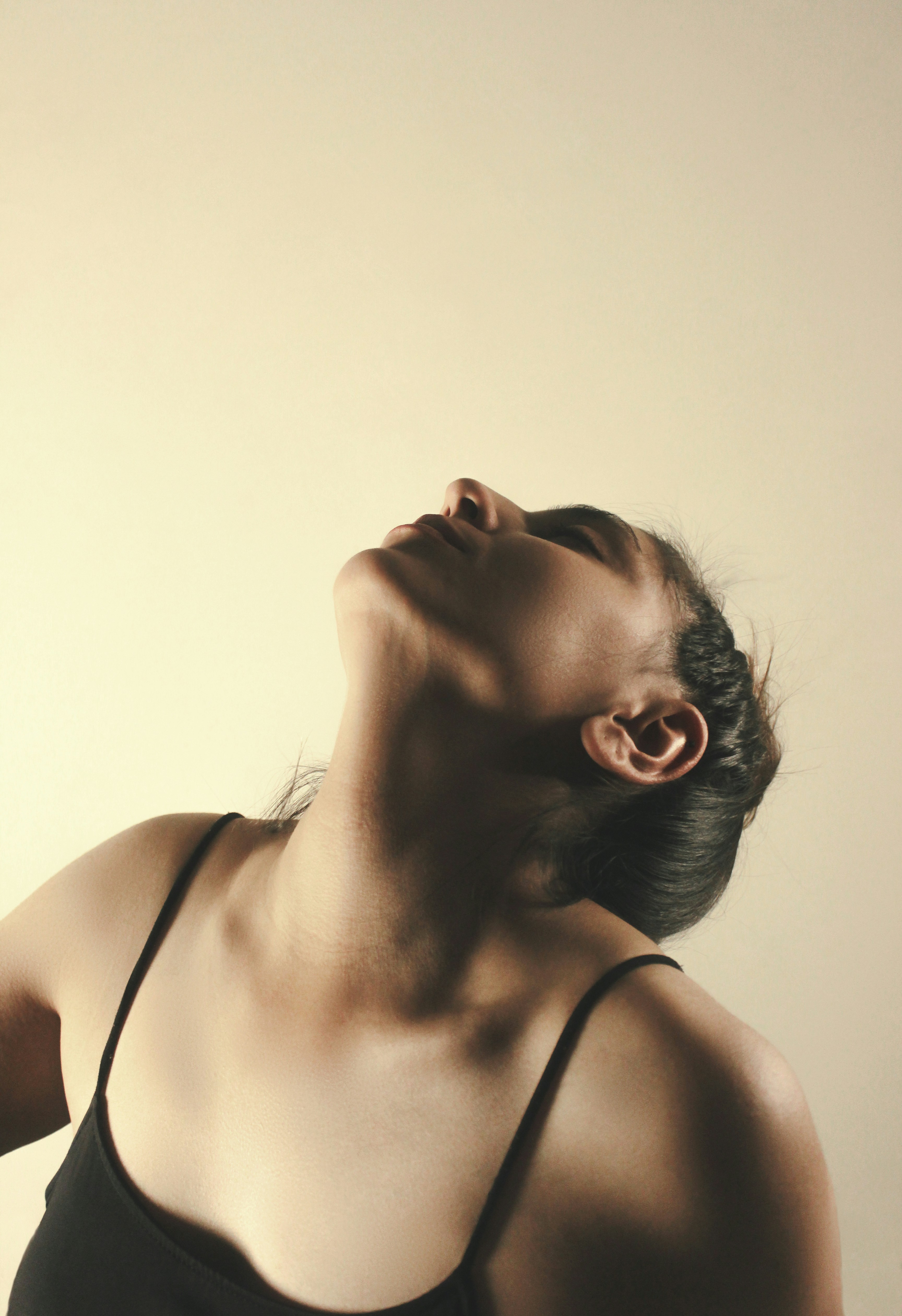 A woman in a black tank top with her head tilted back