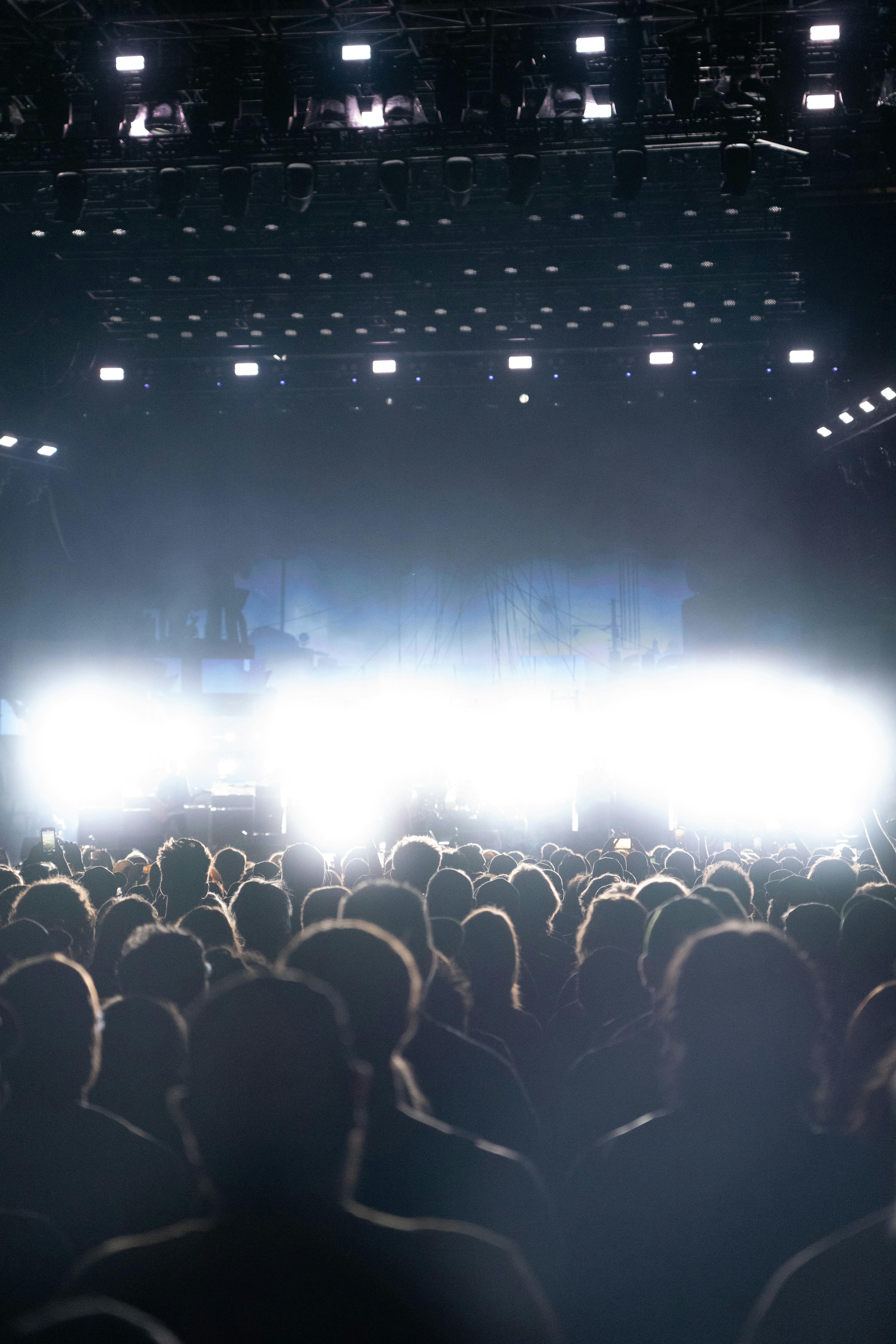Una multitud de personas recortadas contra las brillantes luces del escenario en un concierto