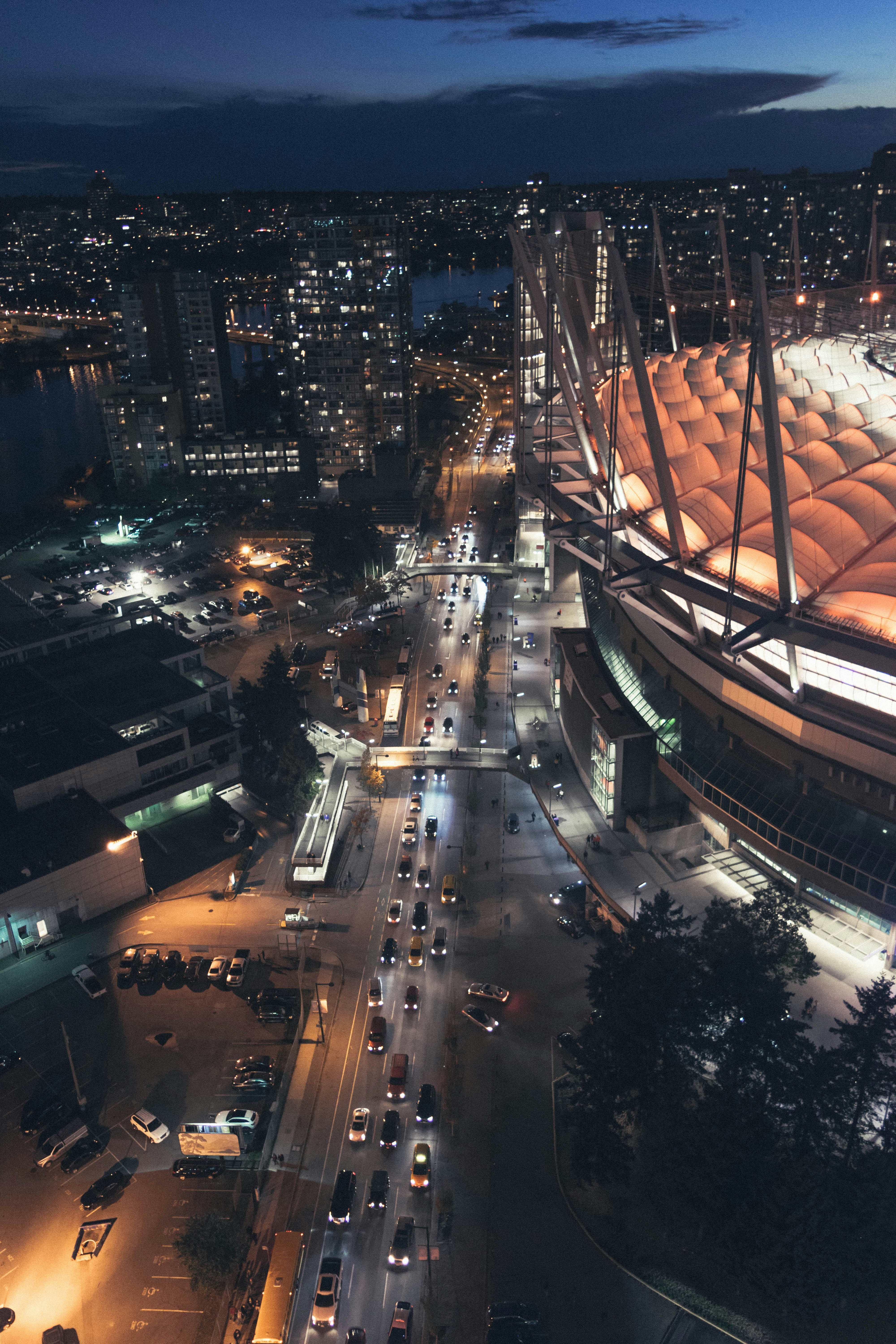 Aerial view of a stadium with a lit roof above a busy city street
