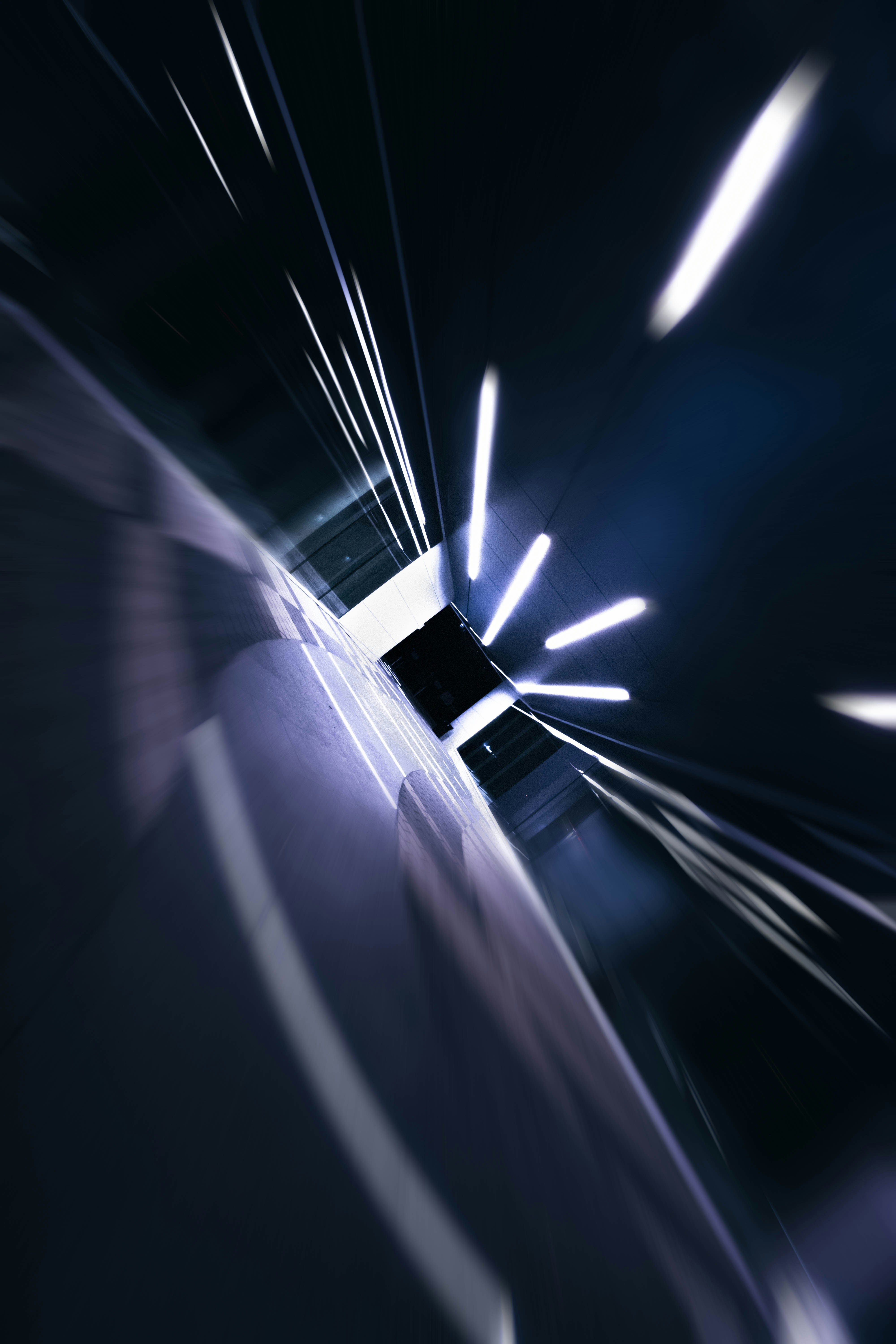 Motion blur of bright white lights in a dark corridor with tiled walls