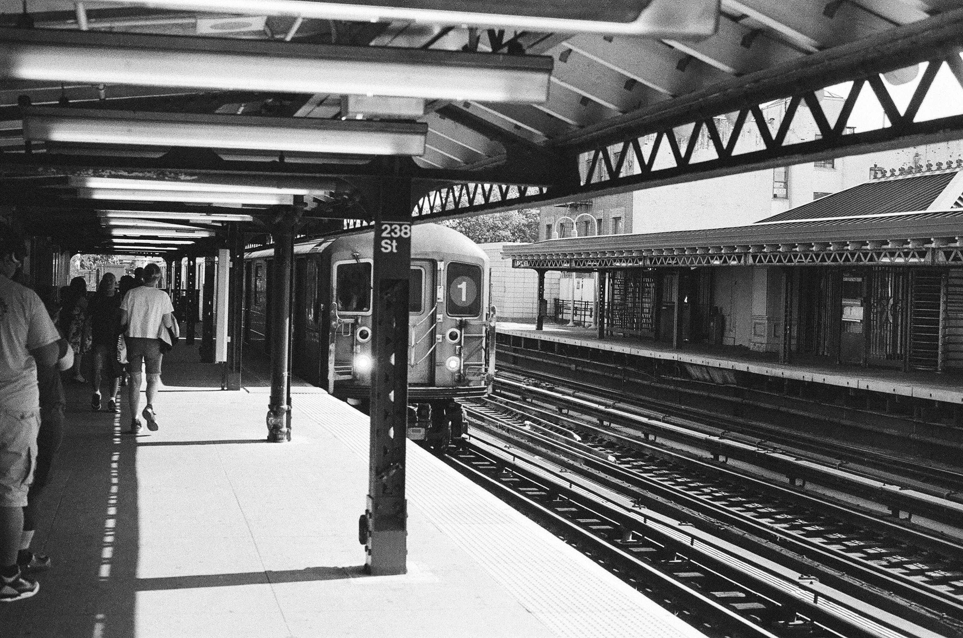 A subway train arriving at a platform with people walking in New York