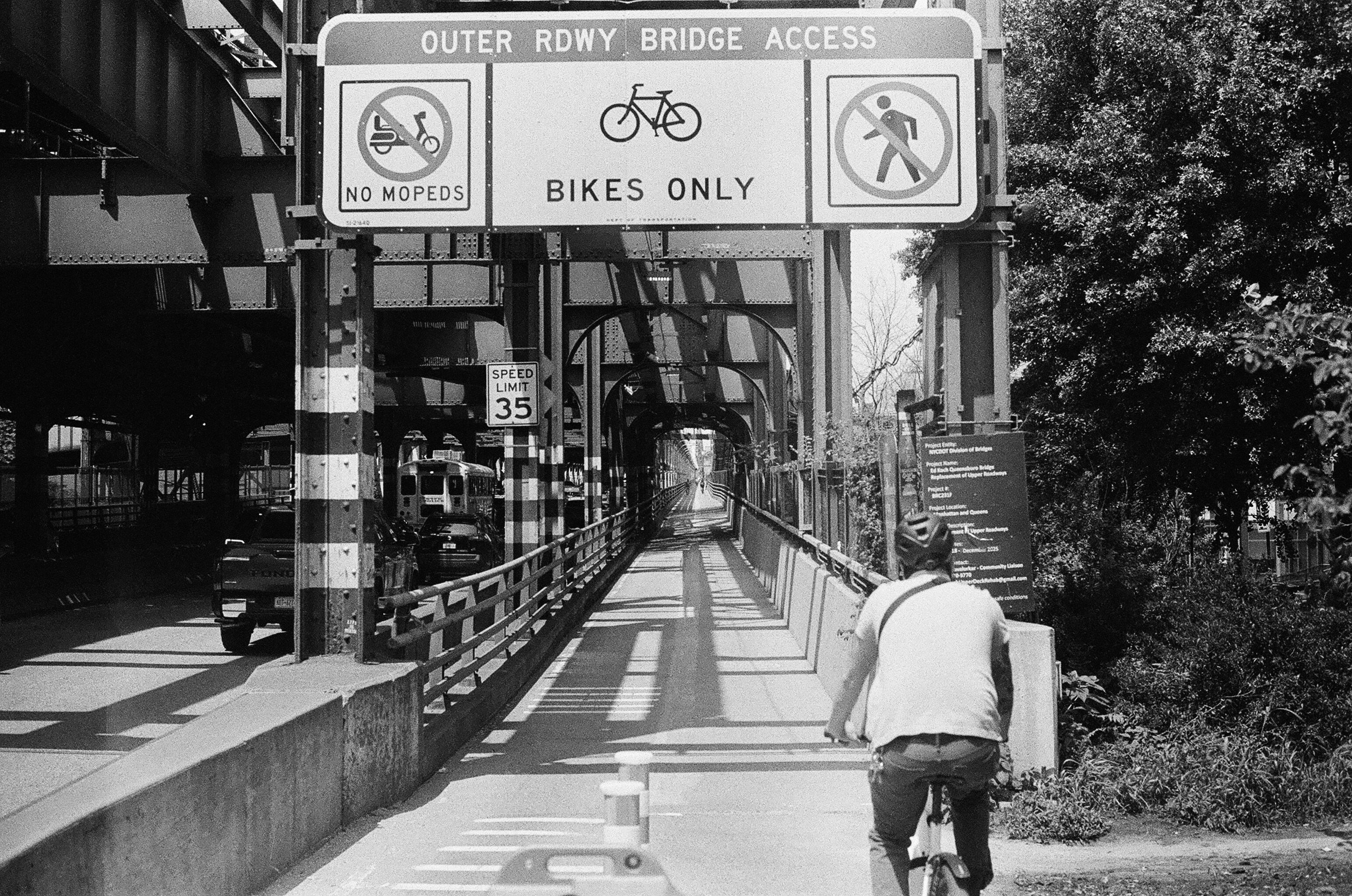A cyclist riding on a bridge path marked with a BIKES ONLY sign