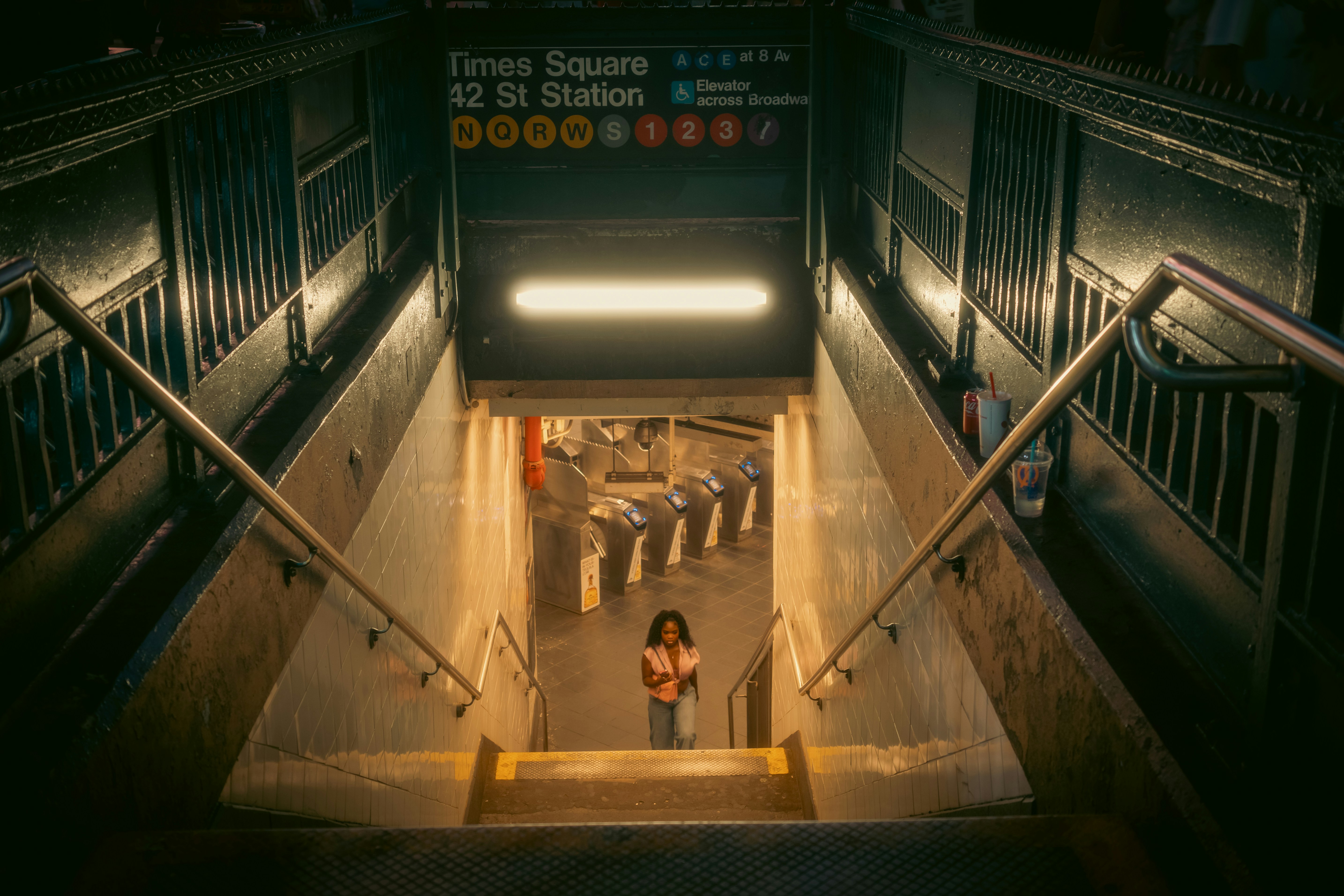 A person walking up the stairs of the Times Square 42 St subway station