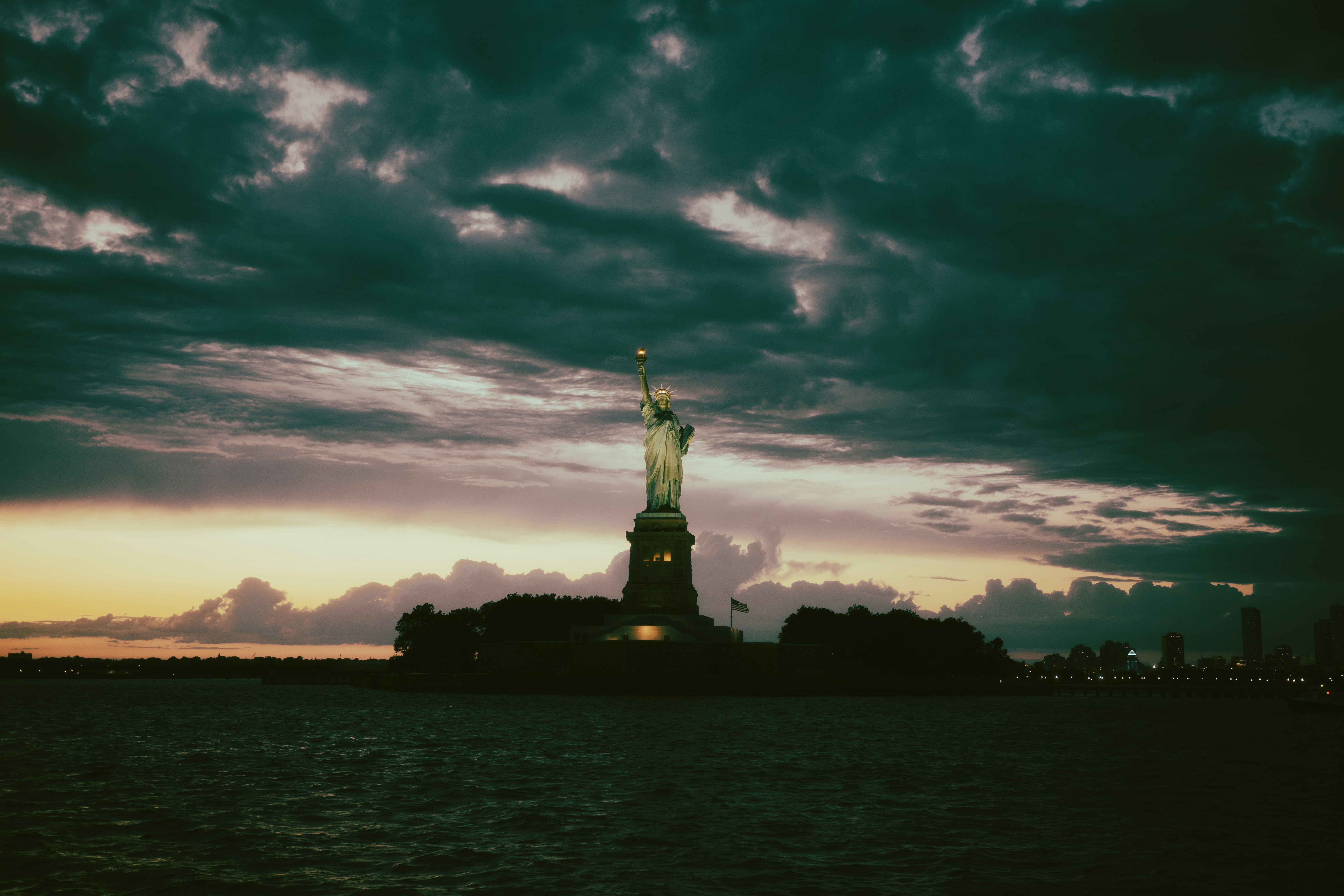 The Statue of Liberty in New York Harbor under a dark cloudy sky