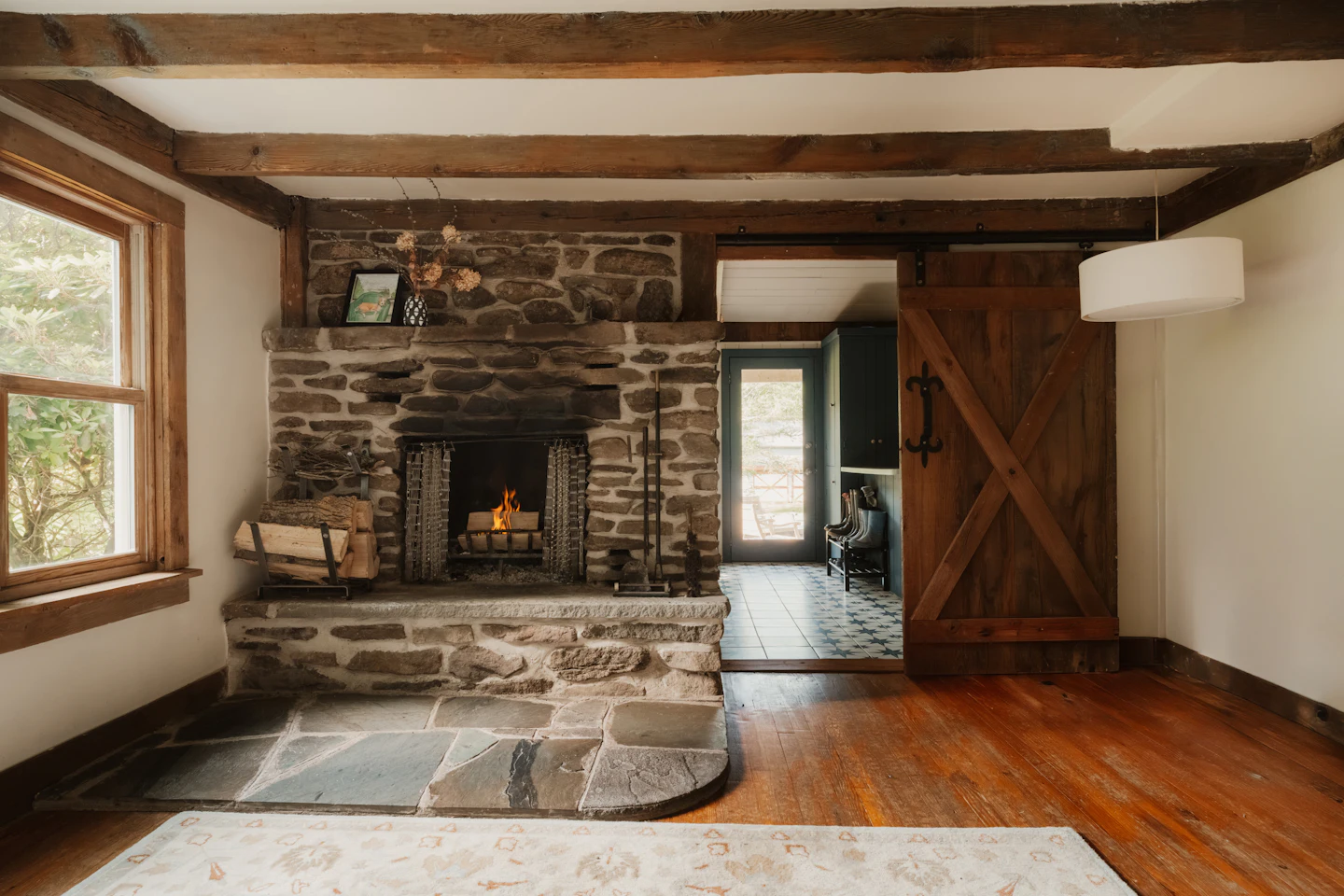 Stone fireplace with a fire burning in a room with wood beams