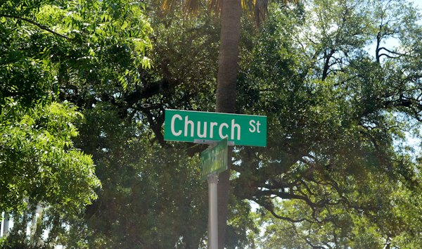 A green street sign reading Church St below a palm tree and leafy trees — Charleston, United States