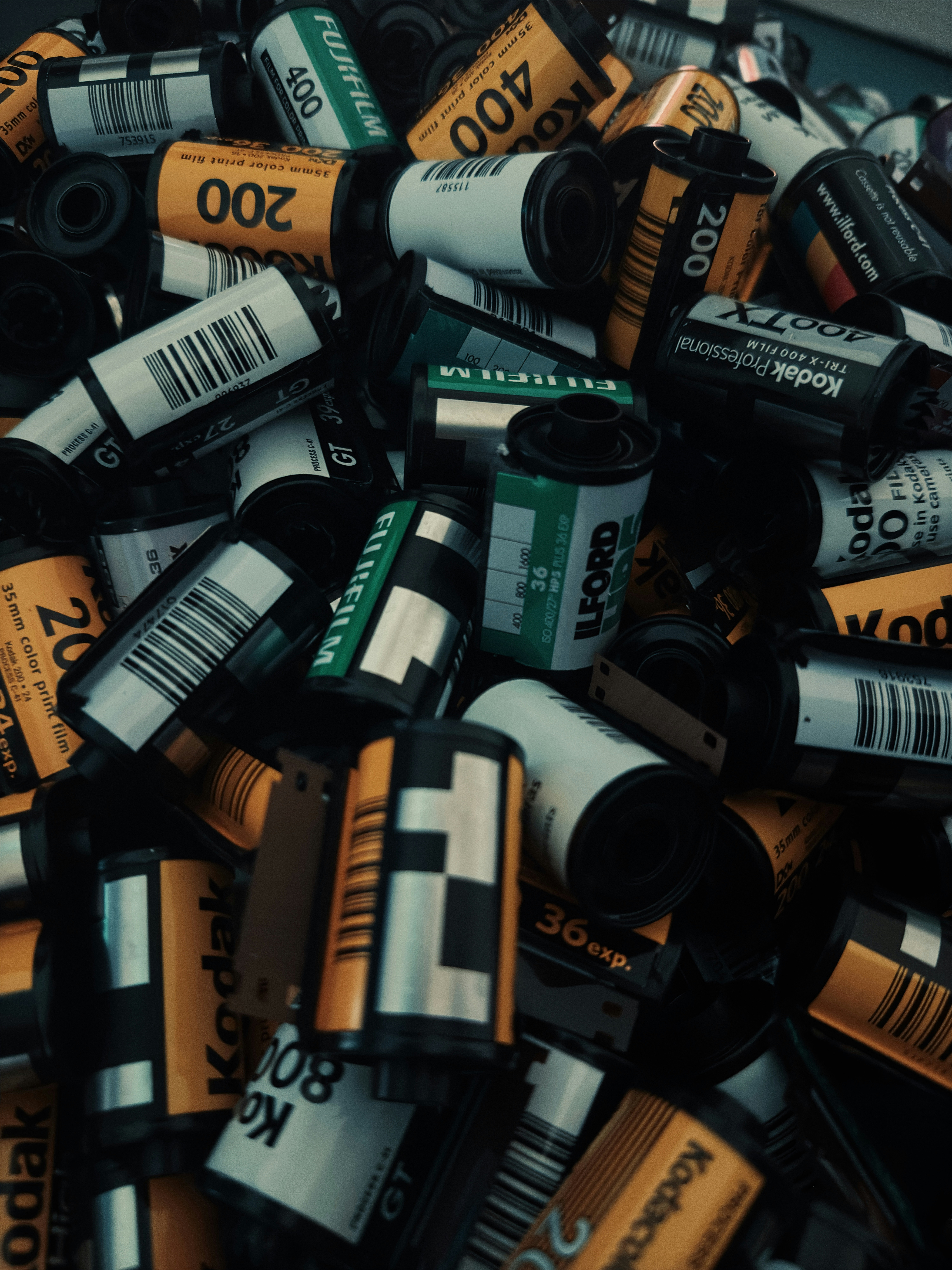 A pile of assorted 35mm film canisters with various brand labels and barcodes