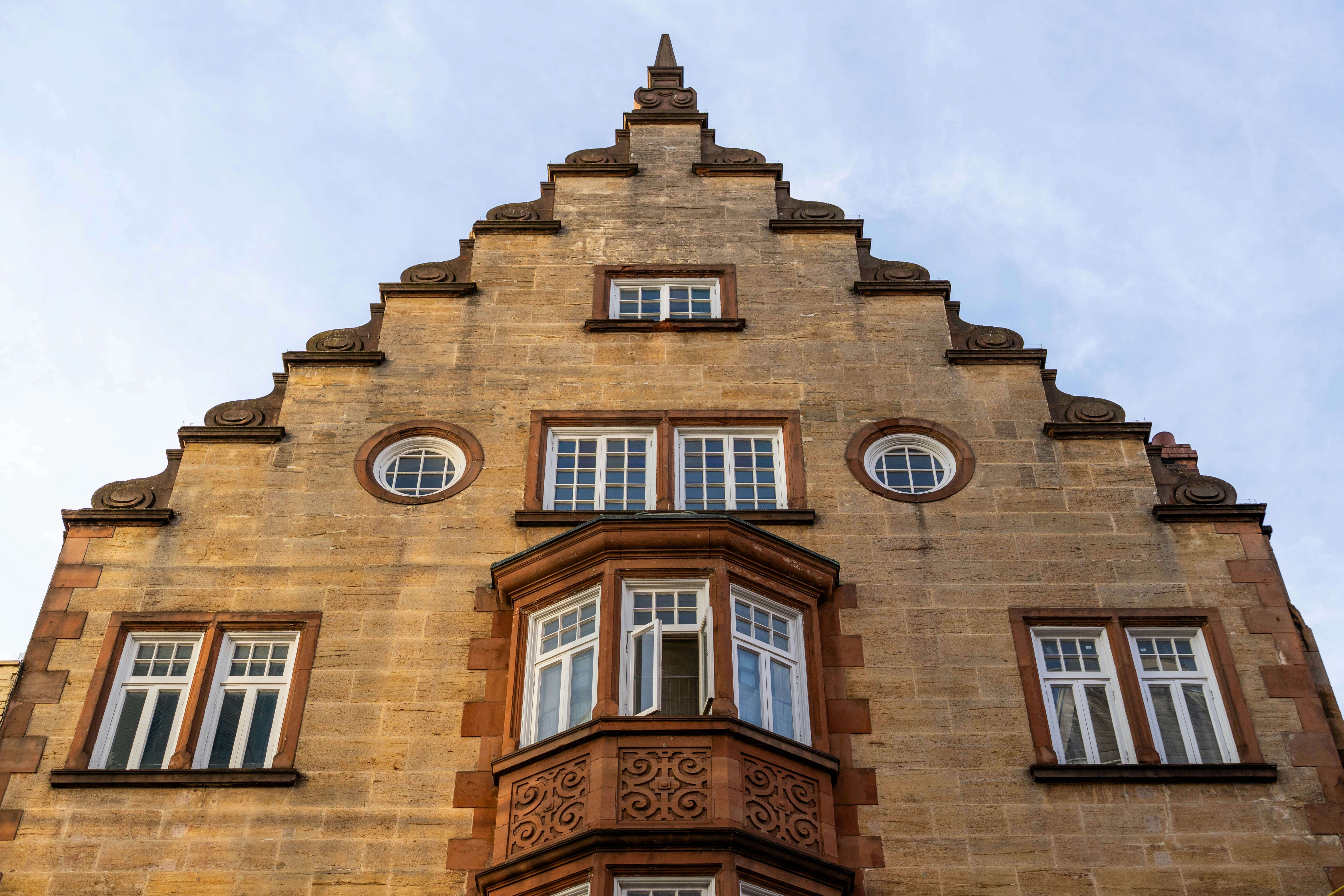 A stone building facade with a stepped gable and a central bay window