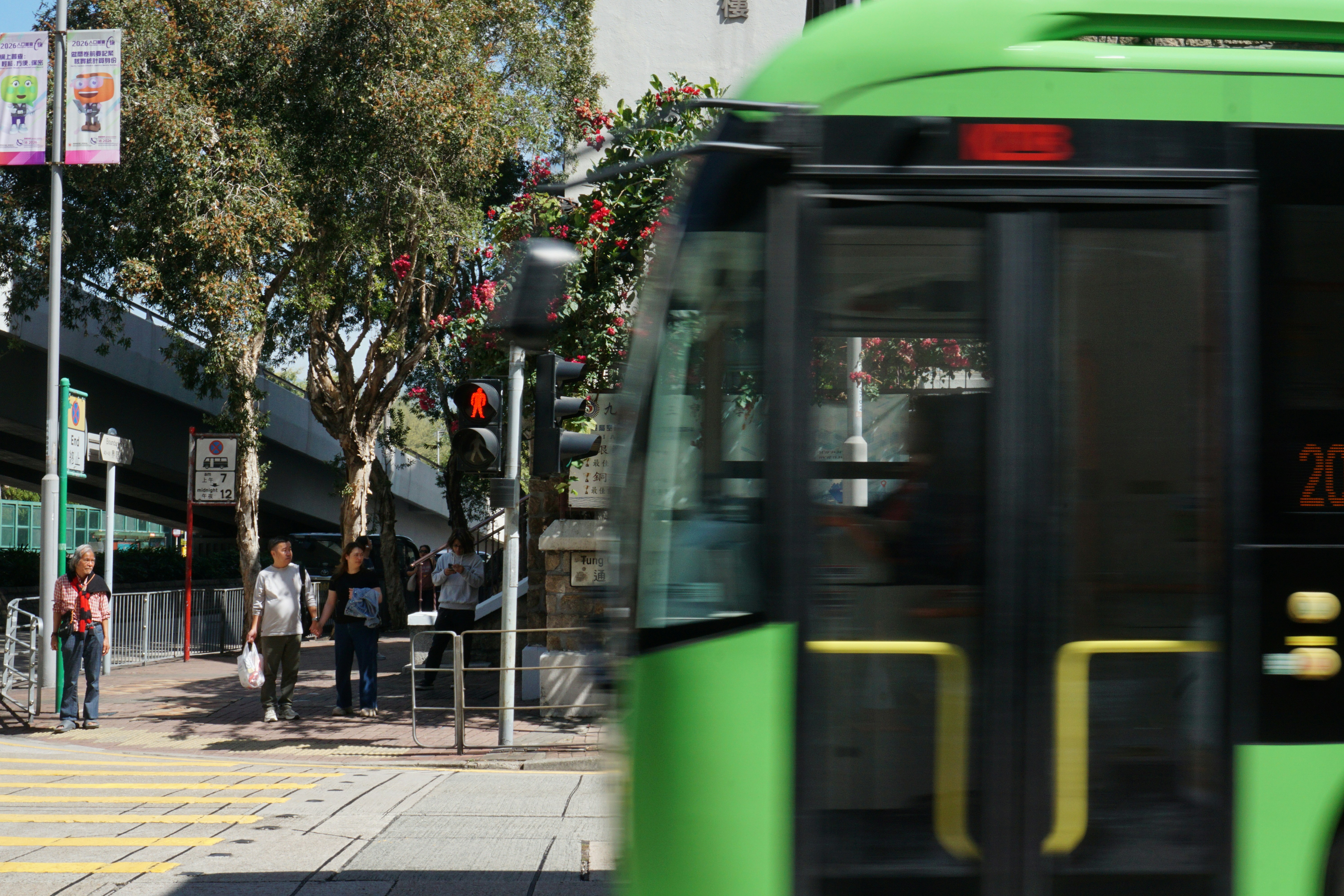 Green bus passing a pedestrian crossing