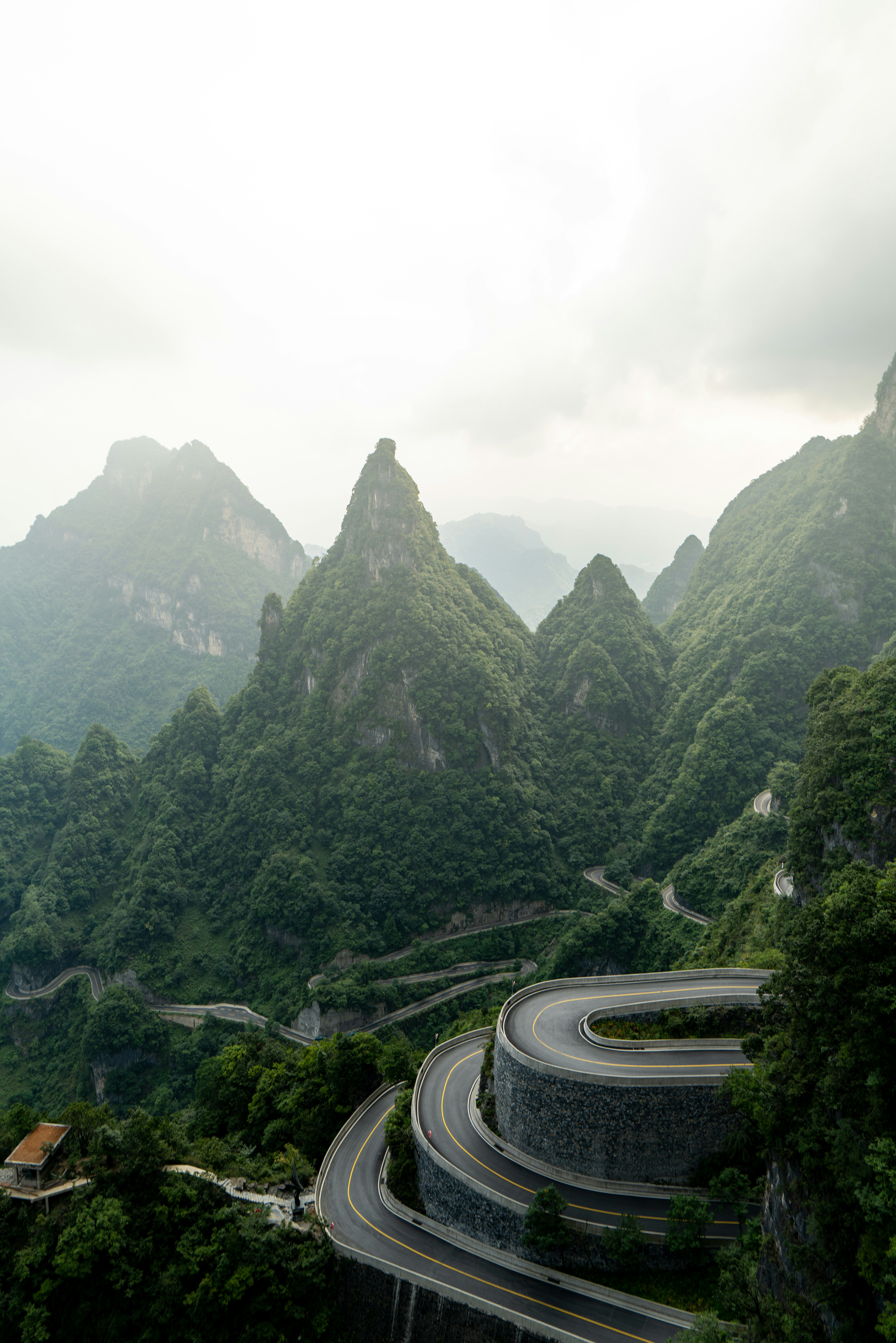 A winding mountain road with sharp hairpin turns through lush green peaks