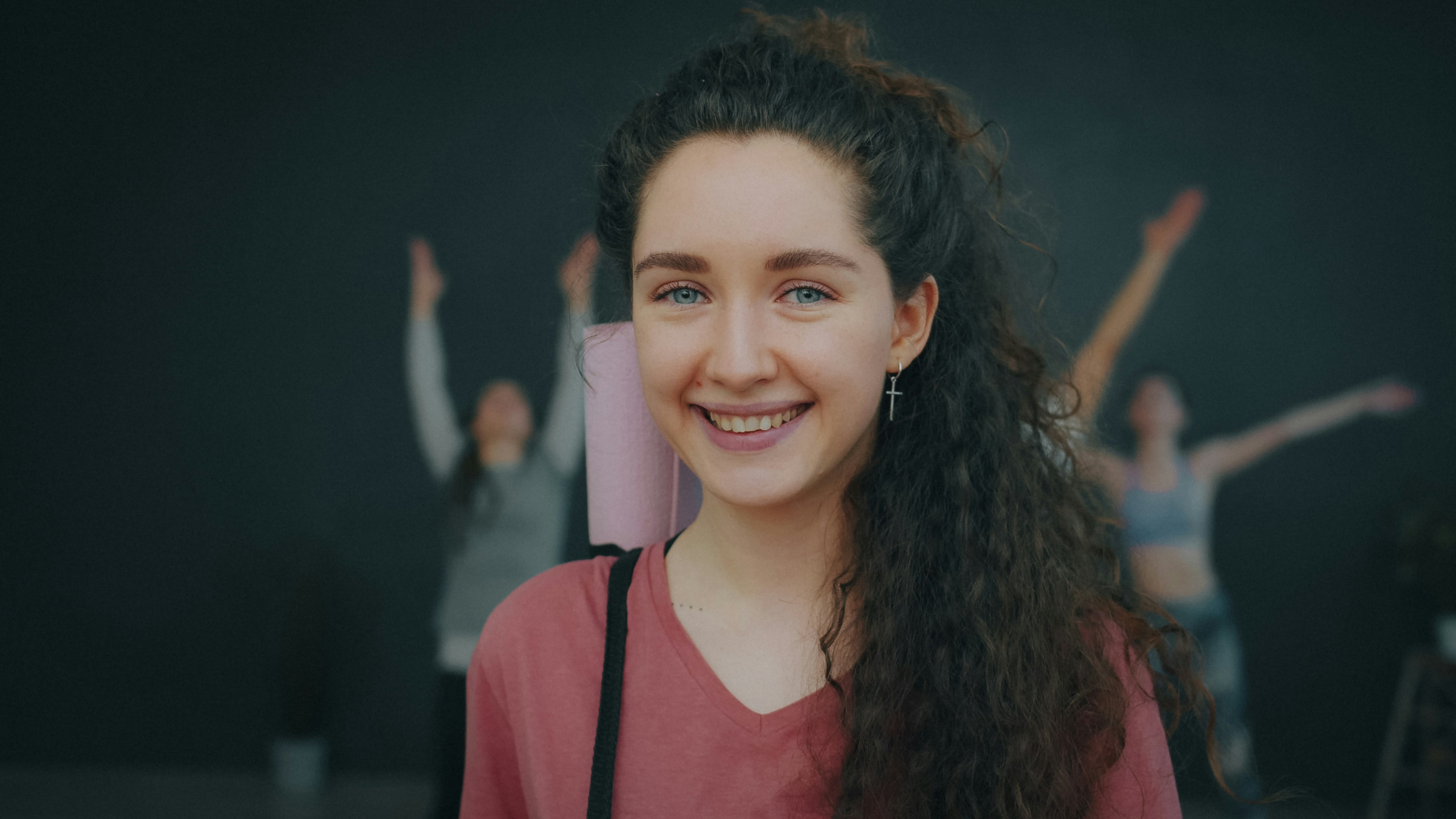 Portrait of charming woman yoga instructor smiling looking at camera in studio in modern sports center. Positive emotions and healthy lifestyle concept.