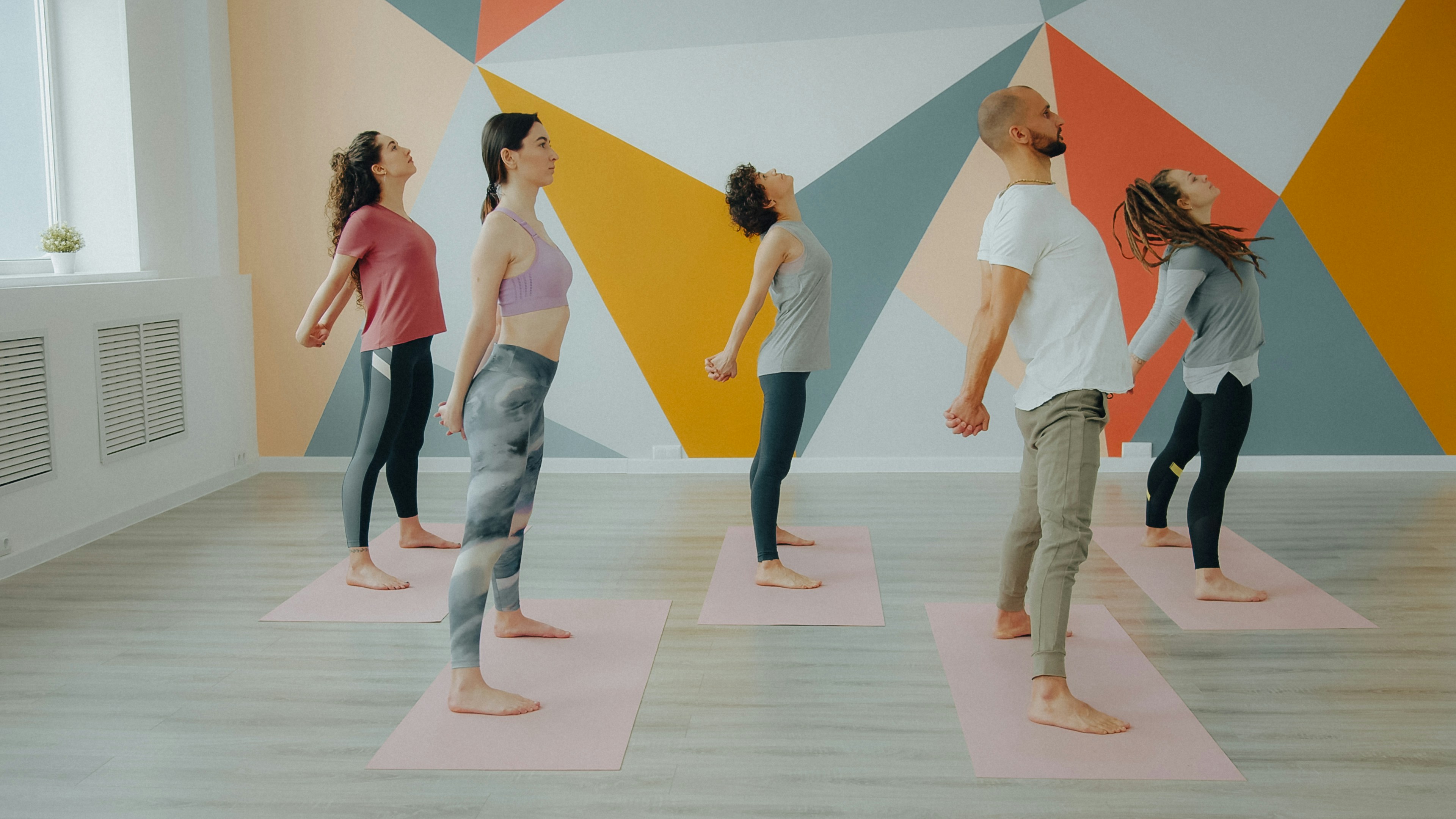 Five people in a yoga studio stretching their arms behind their backs