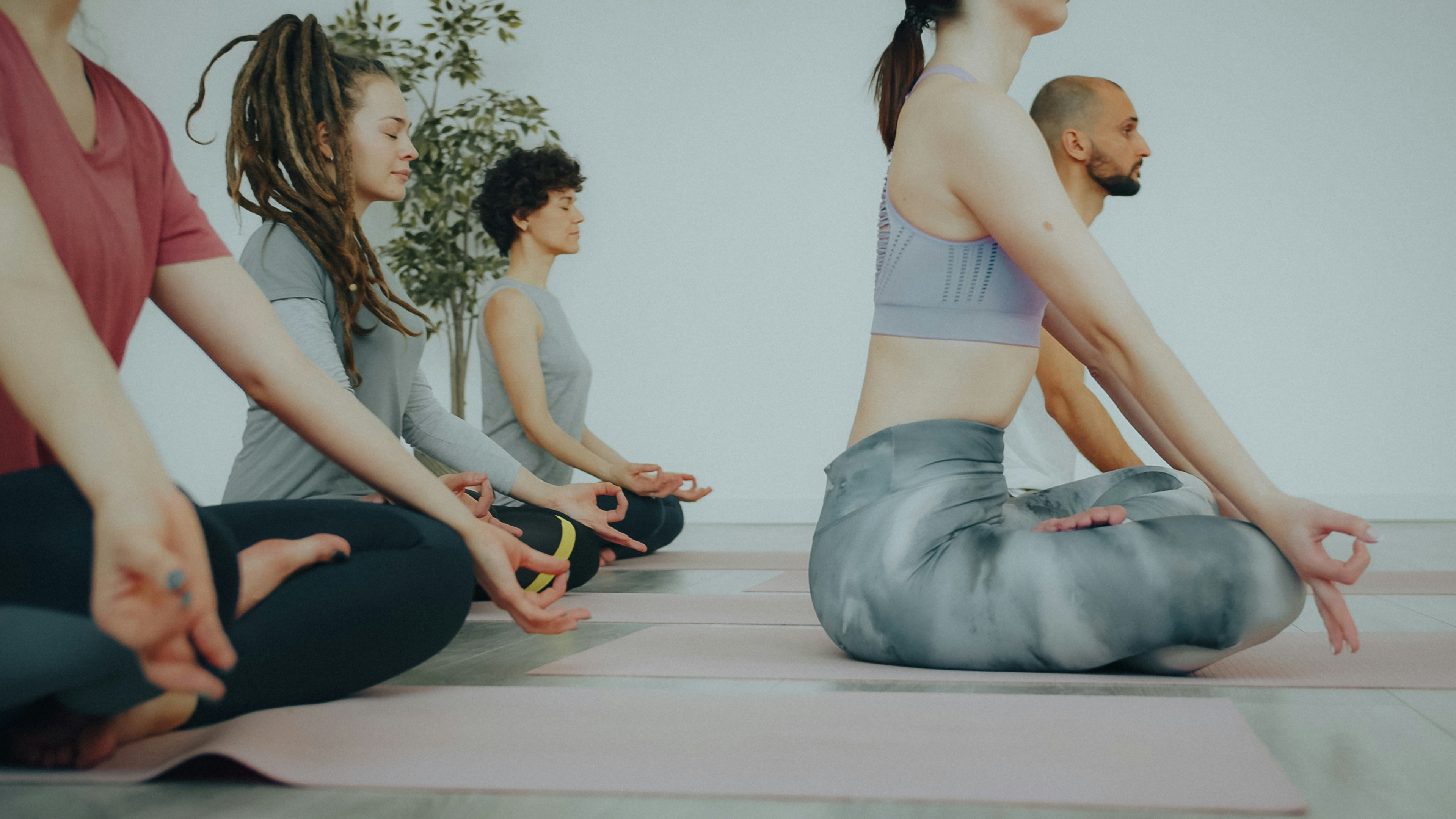 A group of people sitting on yoga mats in a bright studio