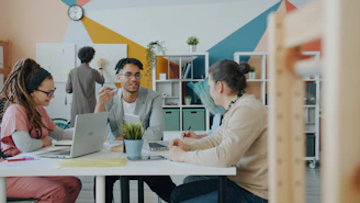 A group of people working together at a table in a colorful office
