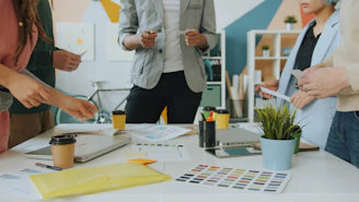 A group of people collaborating around a table with design documents and coffee