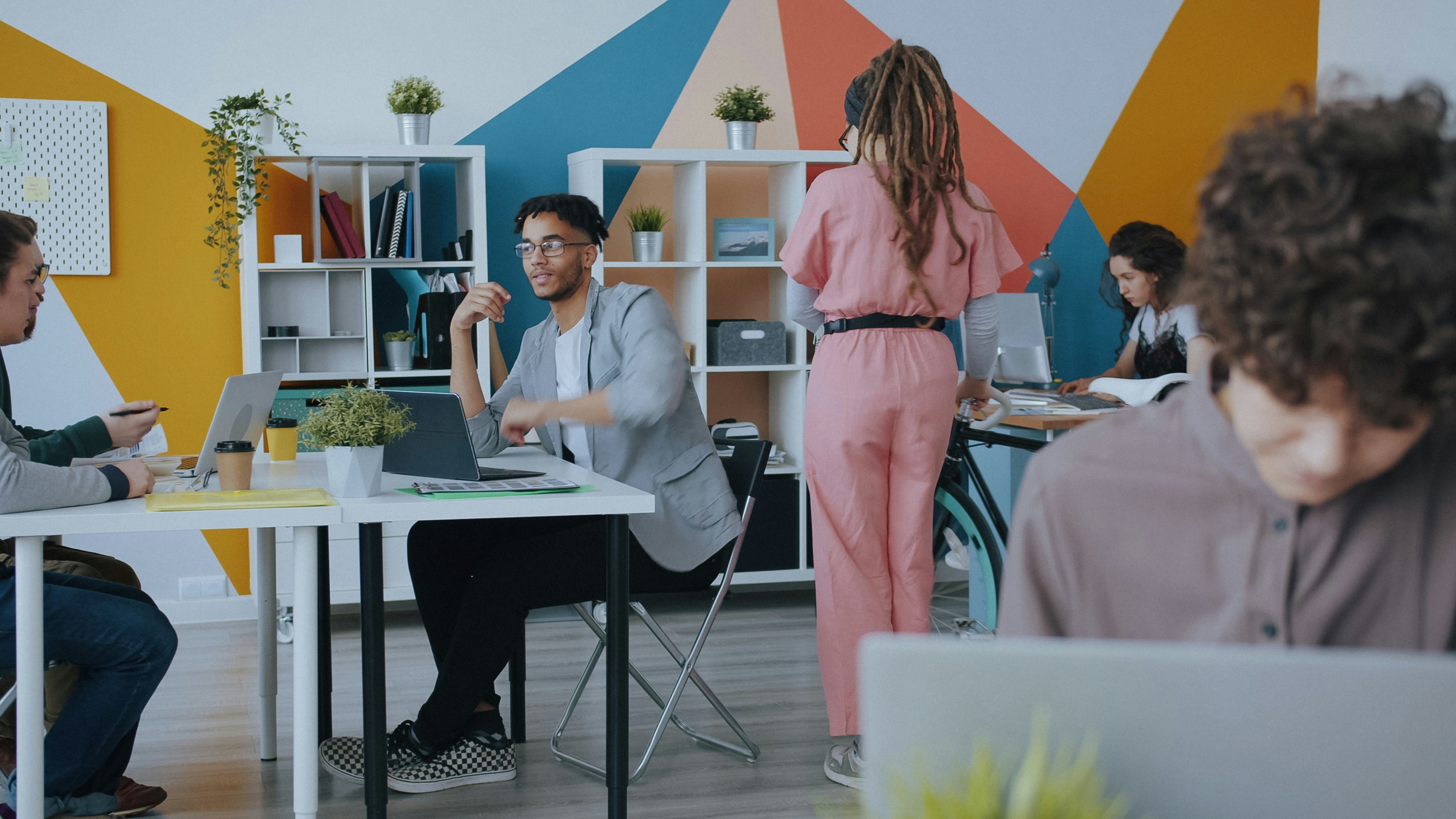 Young businesswoman is coming to work by bike then greeting colleagues with high-five talking discussing project. Healthy lifestyle and active people concept.