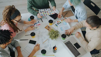 A group of people working together on design projects at a white table