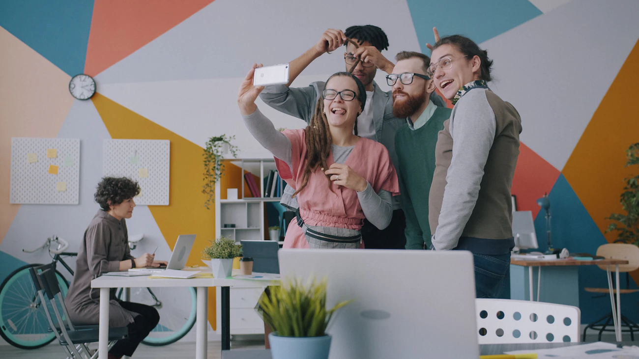 Vier collega's maken een selfie in een kleurrijk kantoor