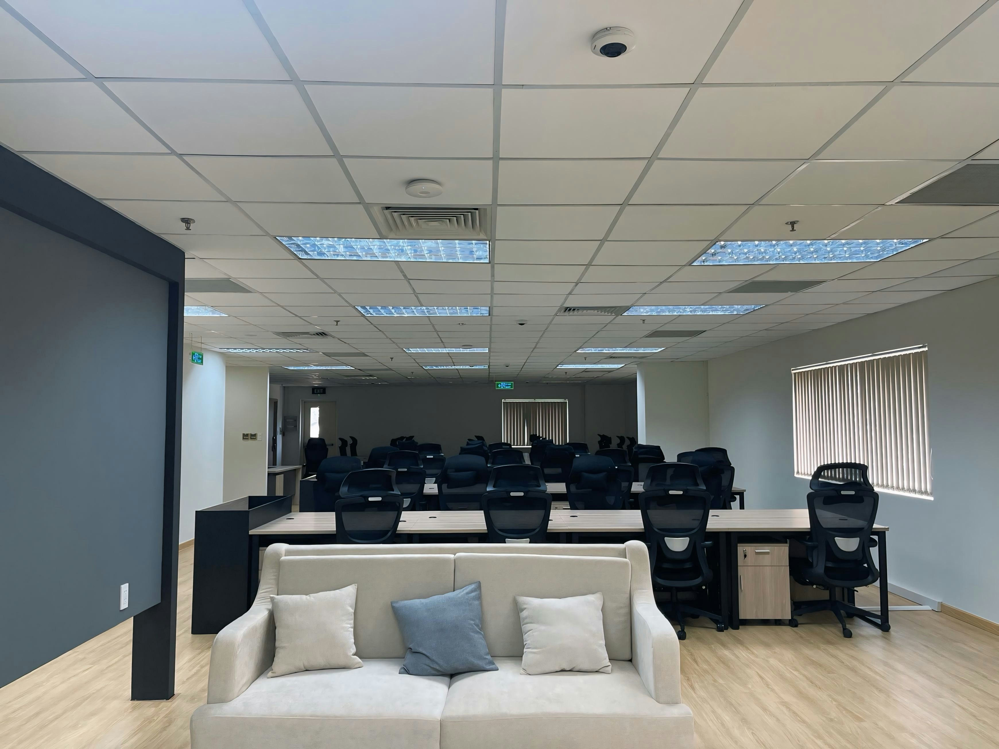 Office with rows of desks and chairs and a reception sofa in the foreground