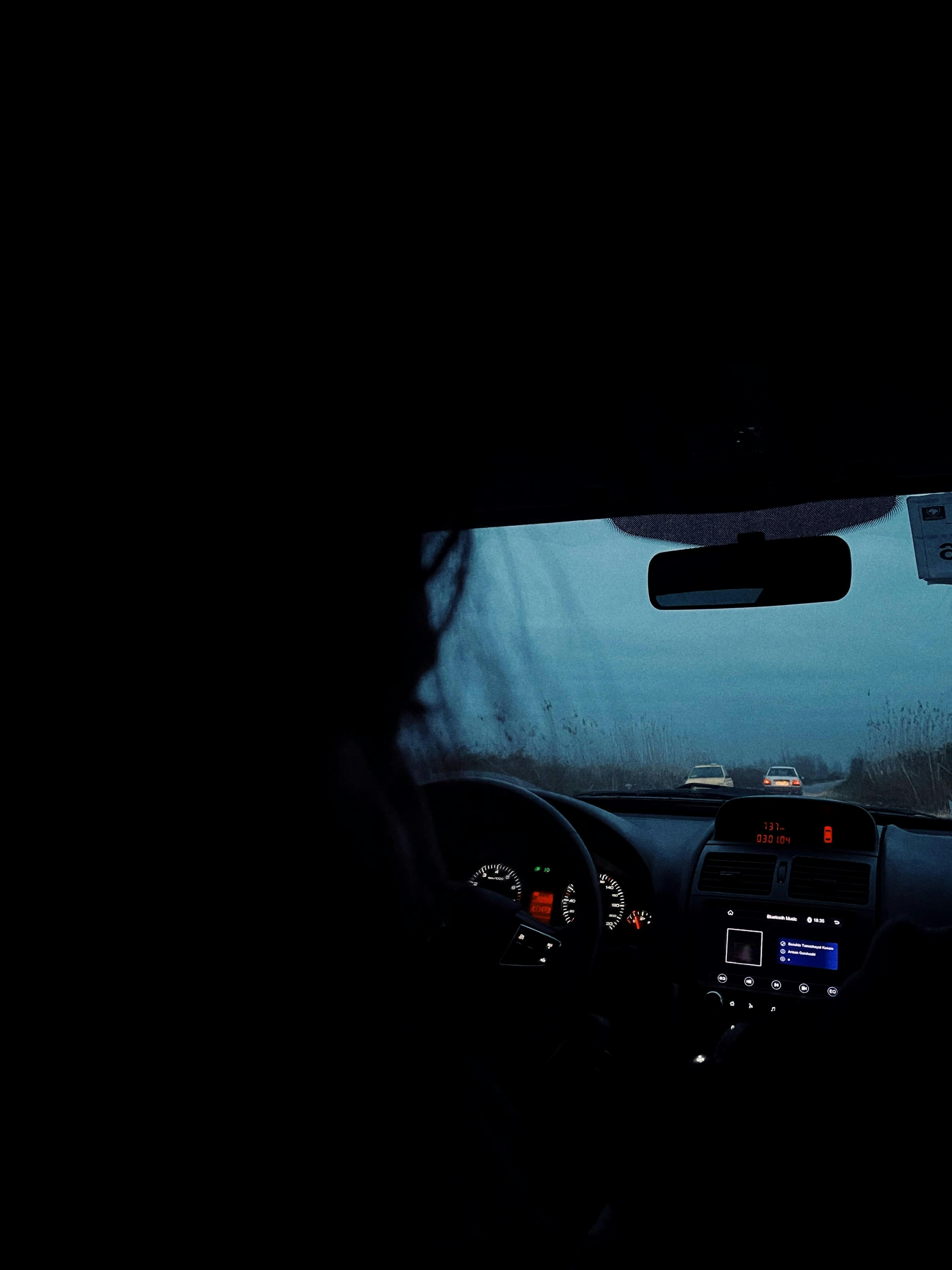 A view from inside a car at night with two vehicles ahead