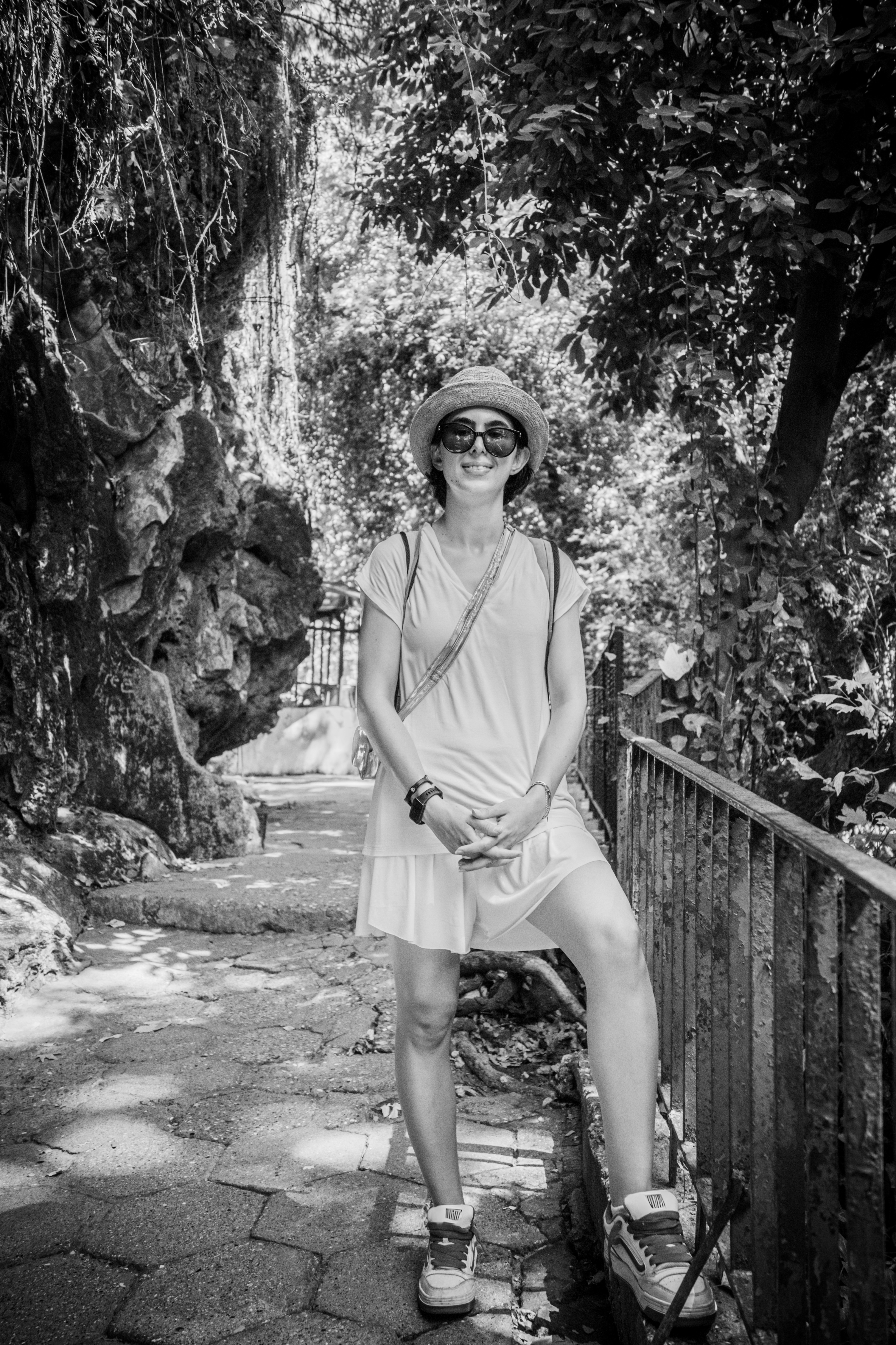 Une femme en chapeau et lunettes de soleil sur un chemin au bord d’une falaise rocheuse