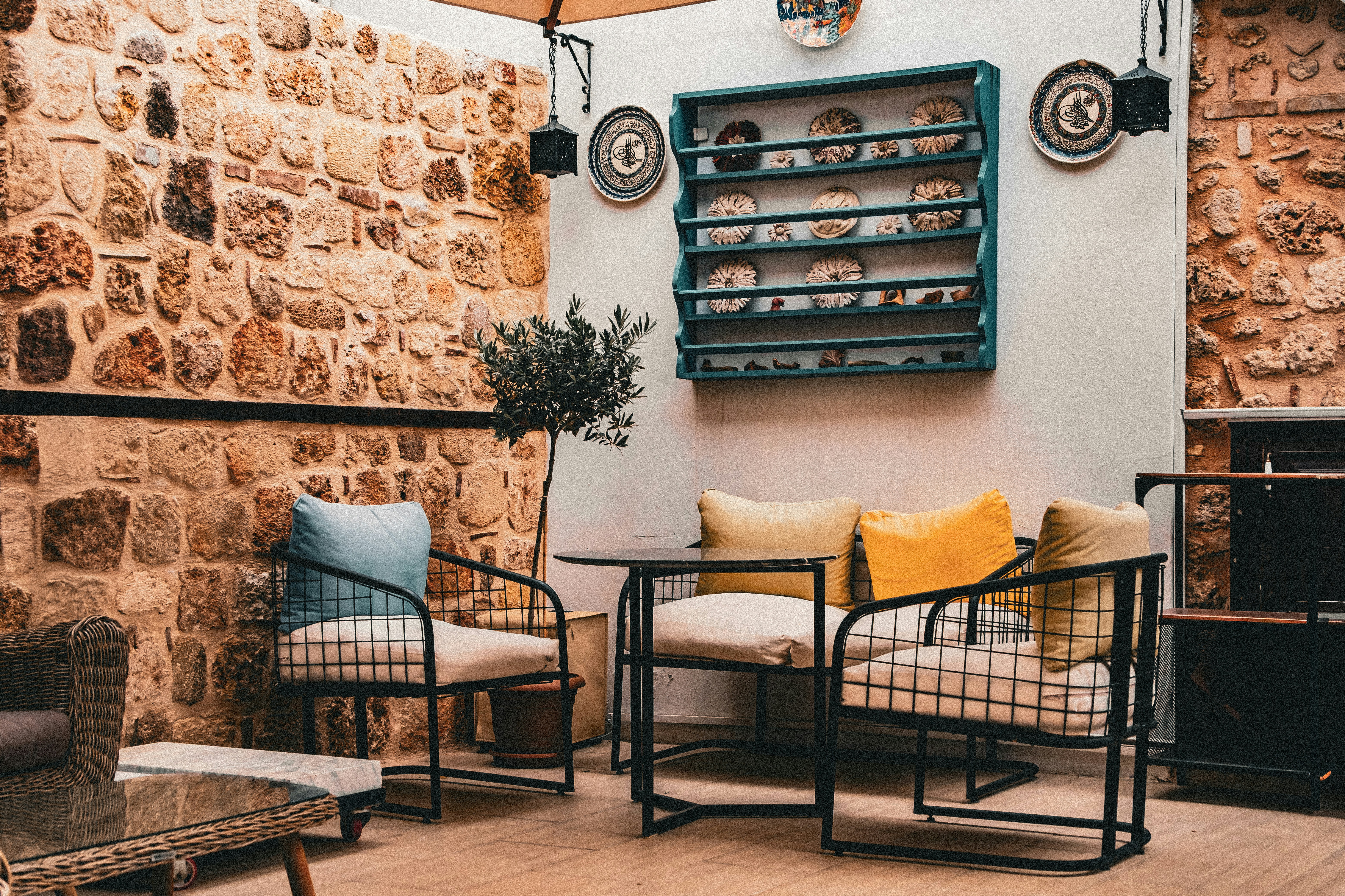 Chaises en métal avec coussins et une petite table contre un mur rustique en pierre
