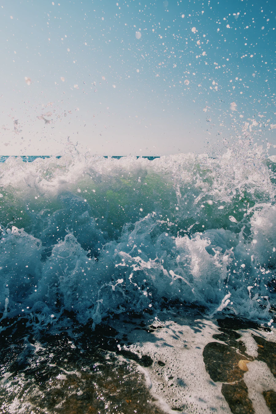 Turquoise seawater surging over dark rock at the edge of a tidal channel