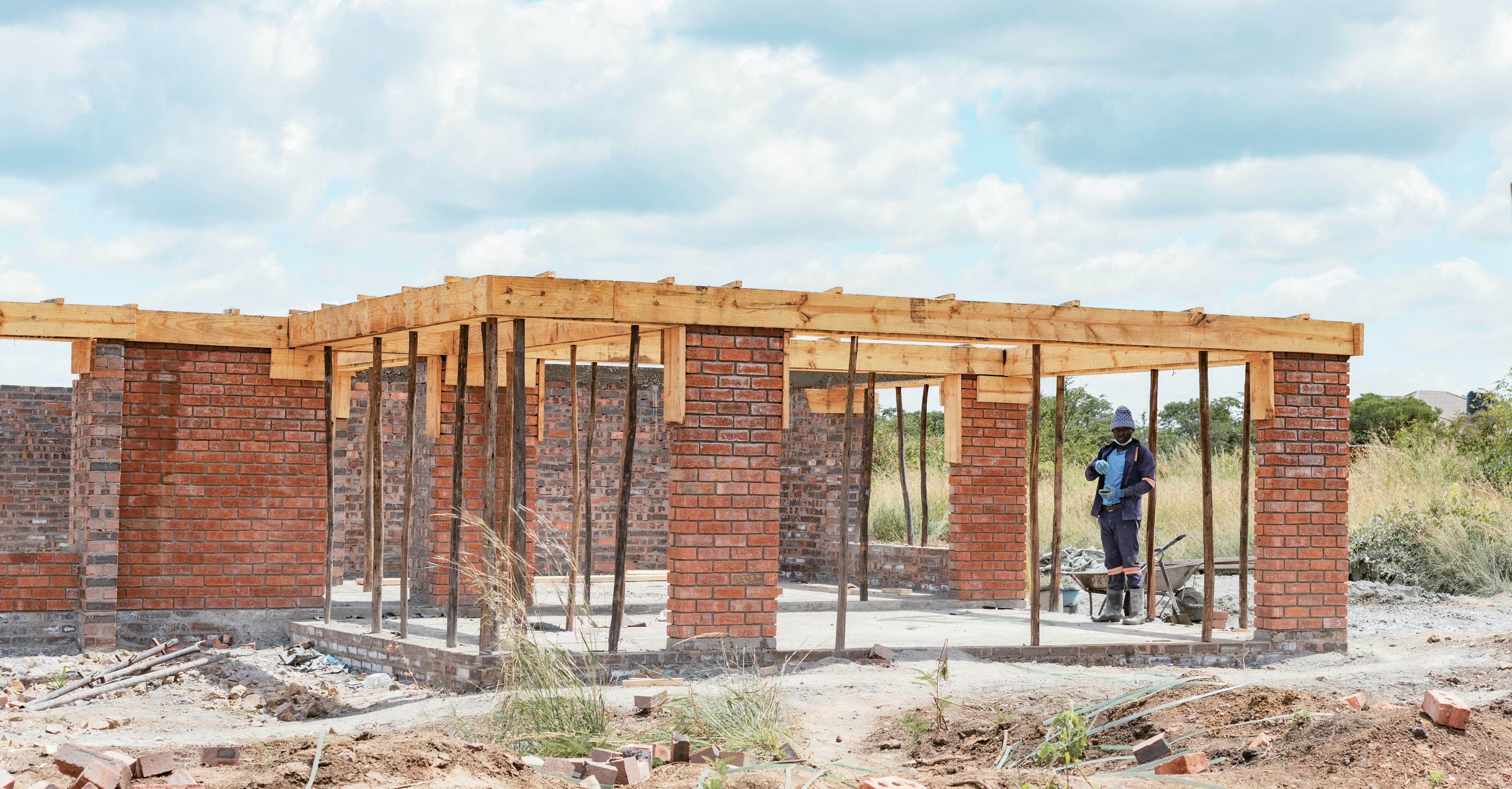 A construction worker in a blue uniform standing inside a brick building frame