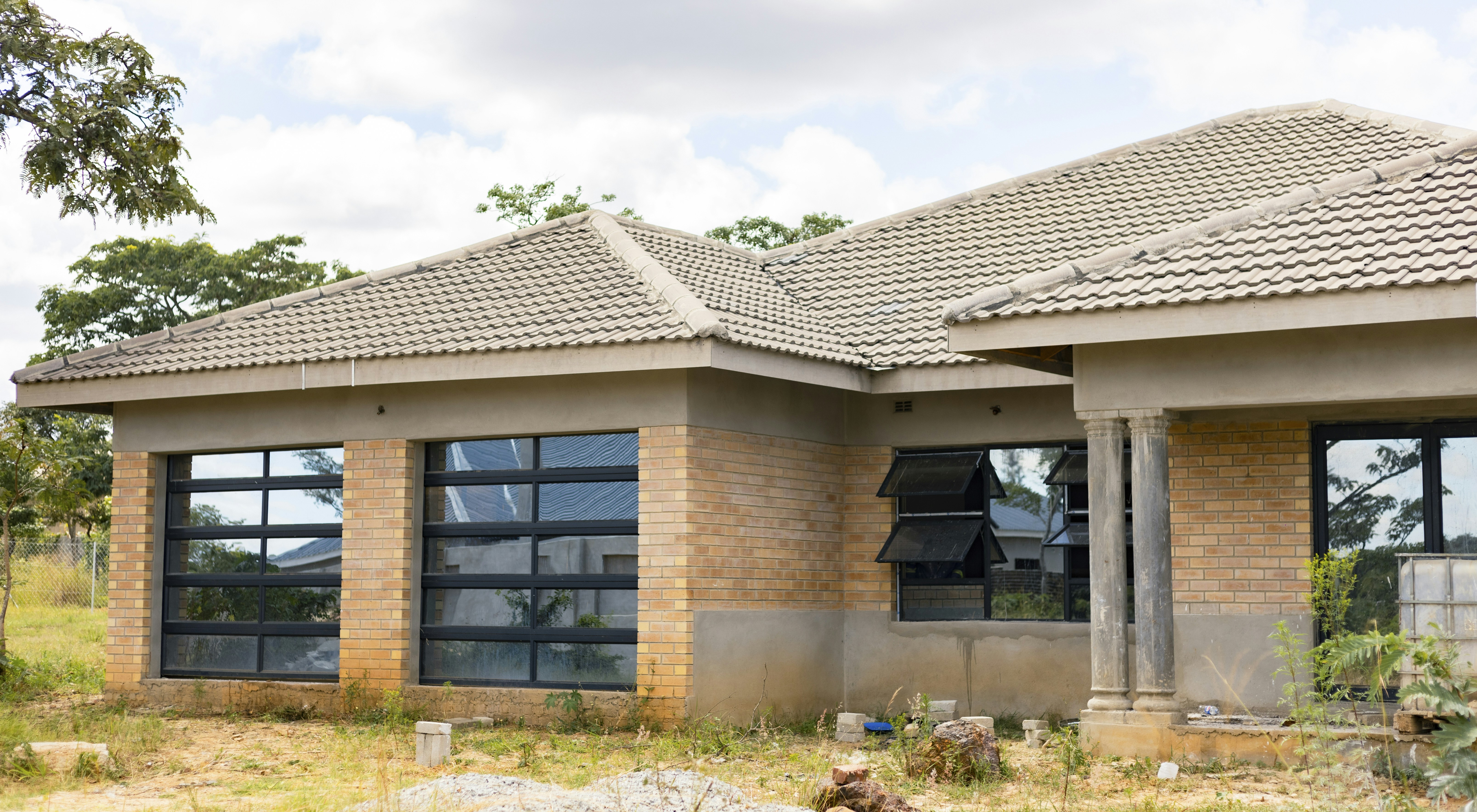 A single-story brick house with a tiled roof and large glass windows