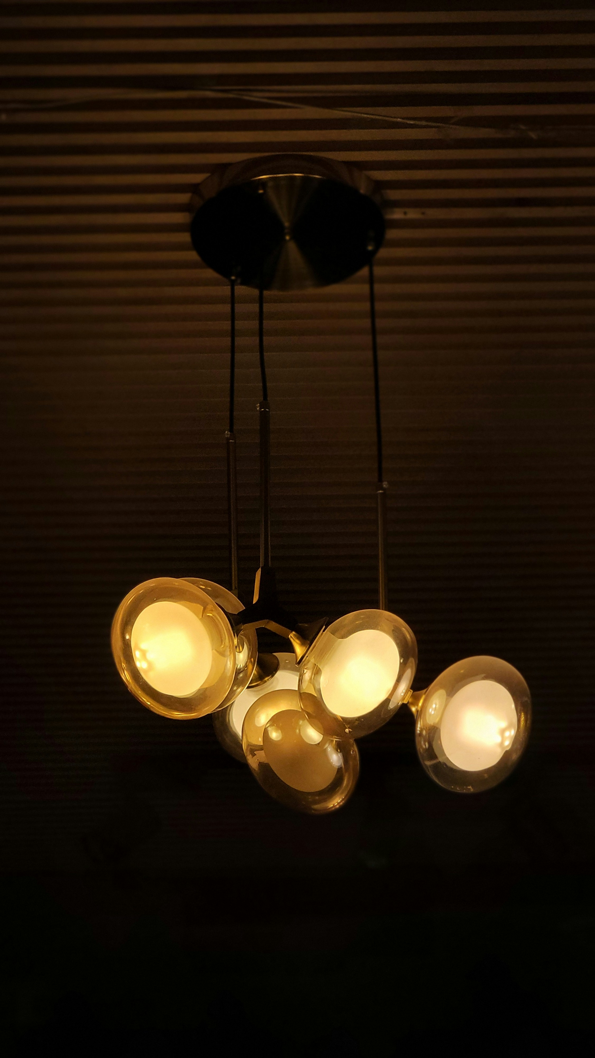 Une suspension moderne avec cinq globes en verre ambré lumineux sur un plafond sombre