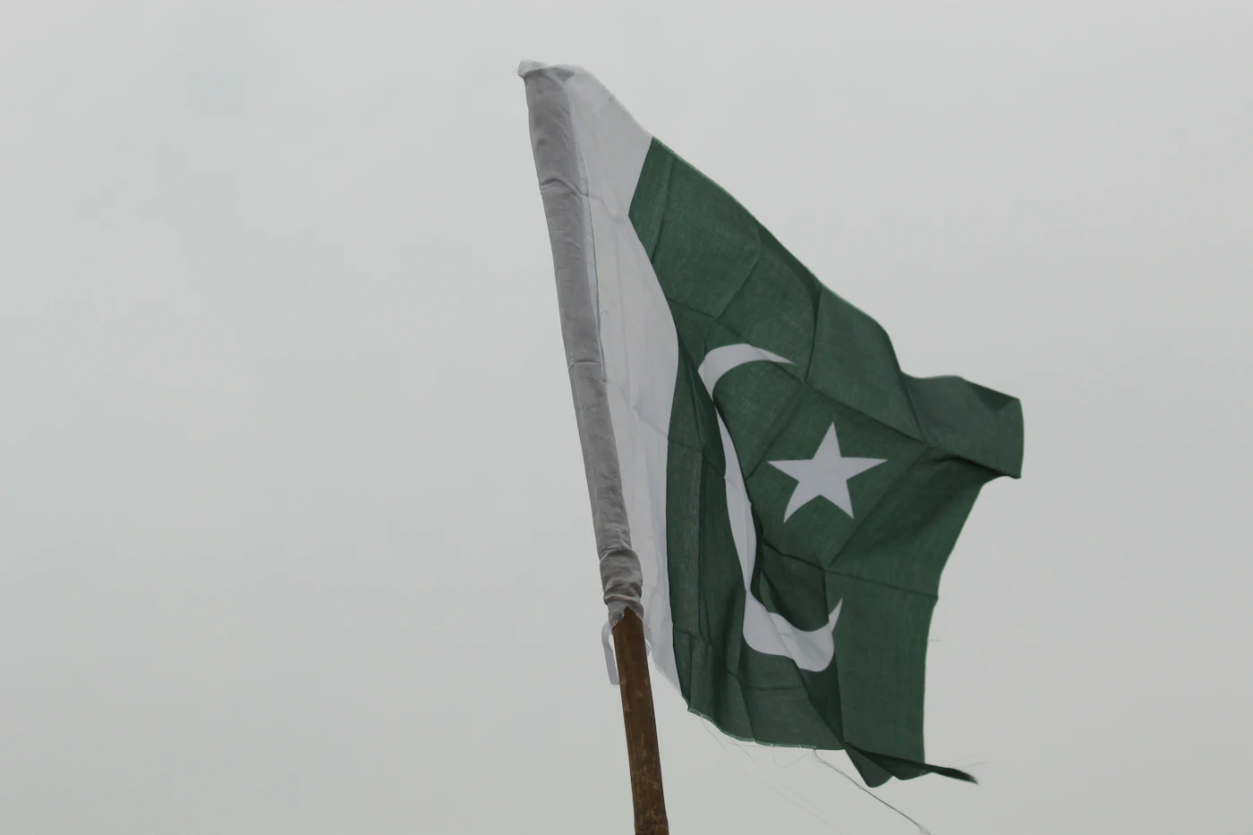 Pakistan flag waving on a wooden pole