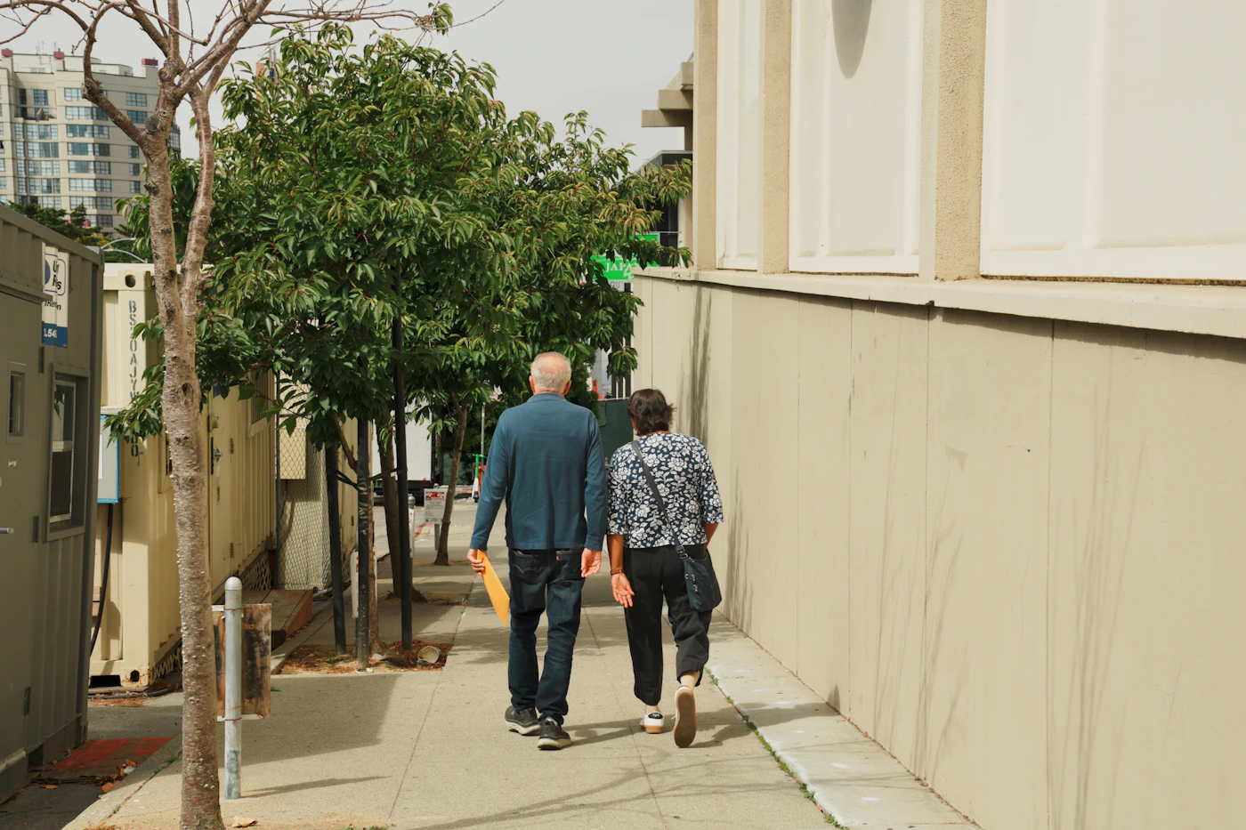 An older couple walking together down a tree-lined path