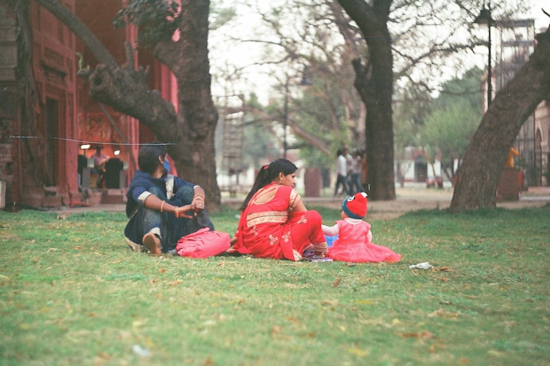 Two women and a baby sitting on the grass in a park