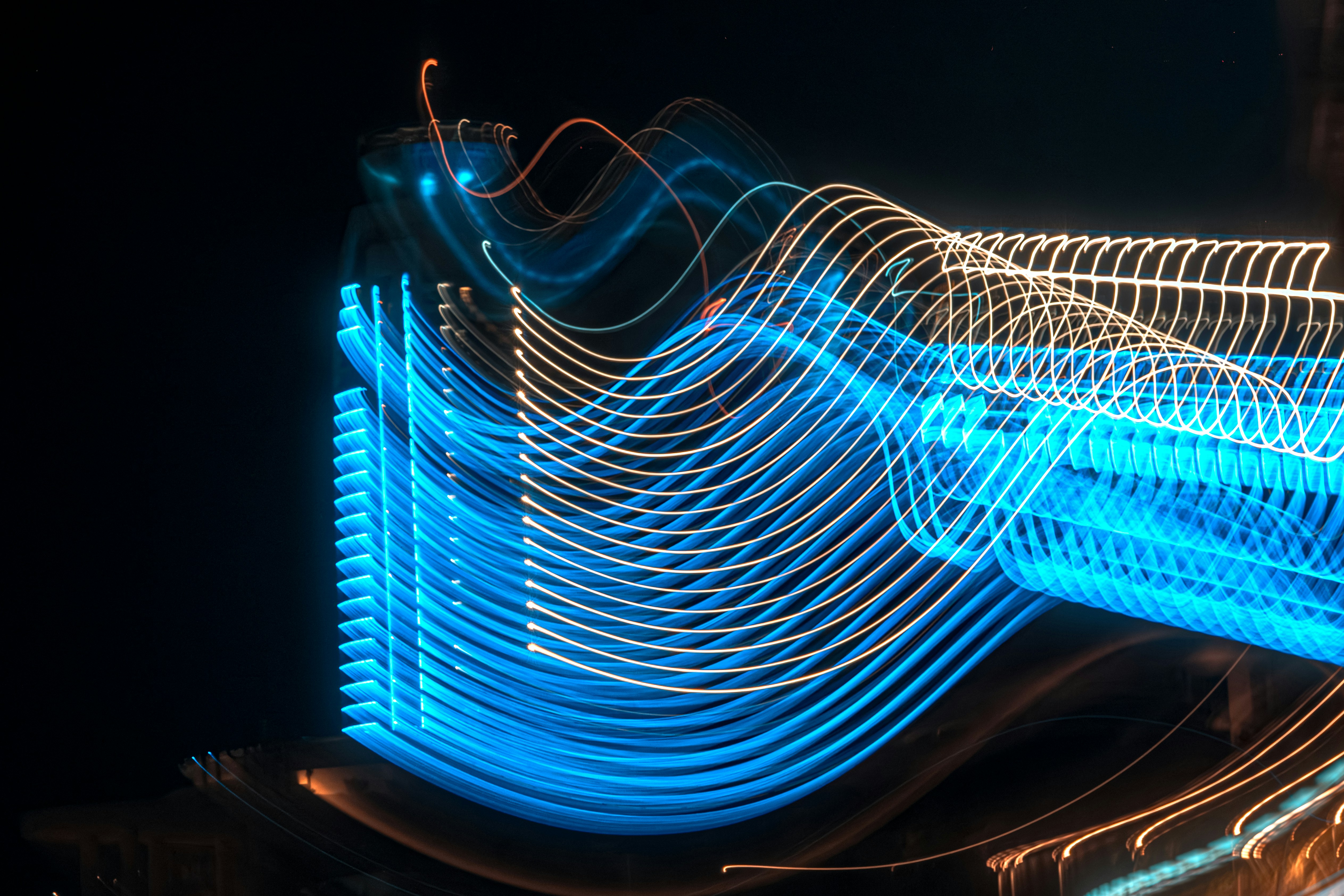Blue and orange light trails in a long exposure against a black background