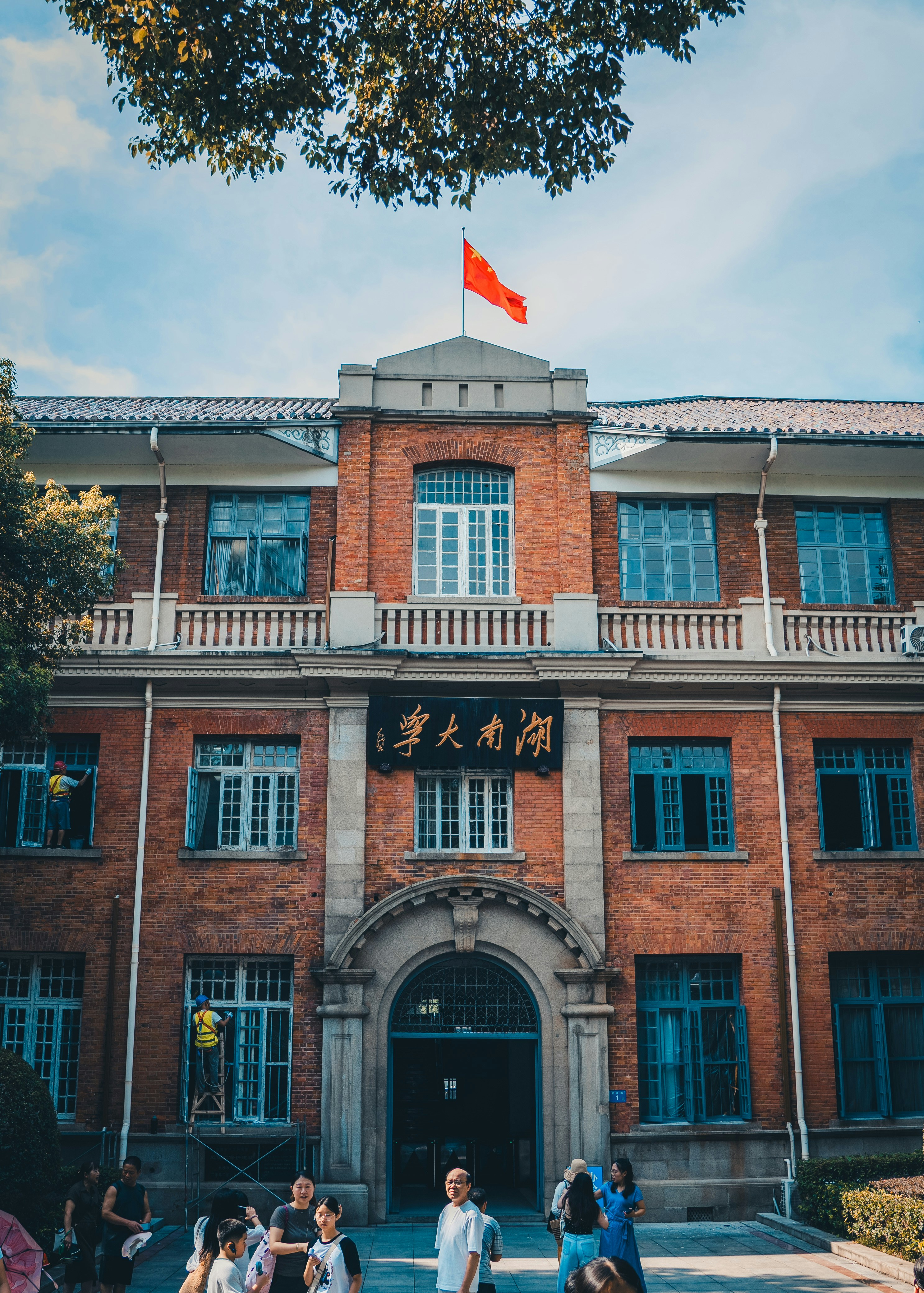 A red brick building with blue windows and a Chinese flag on top