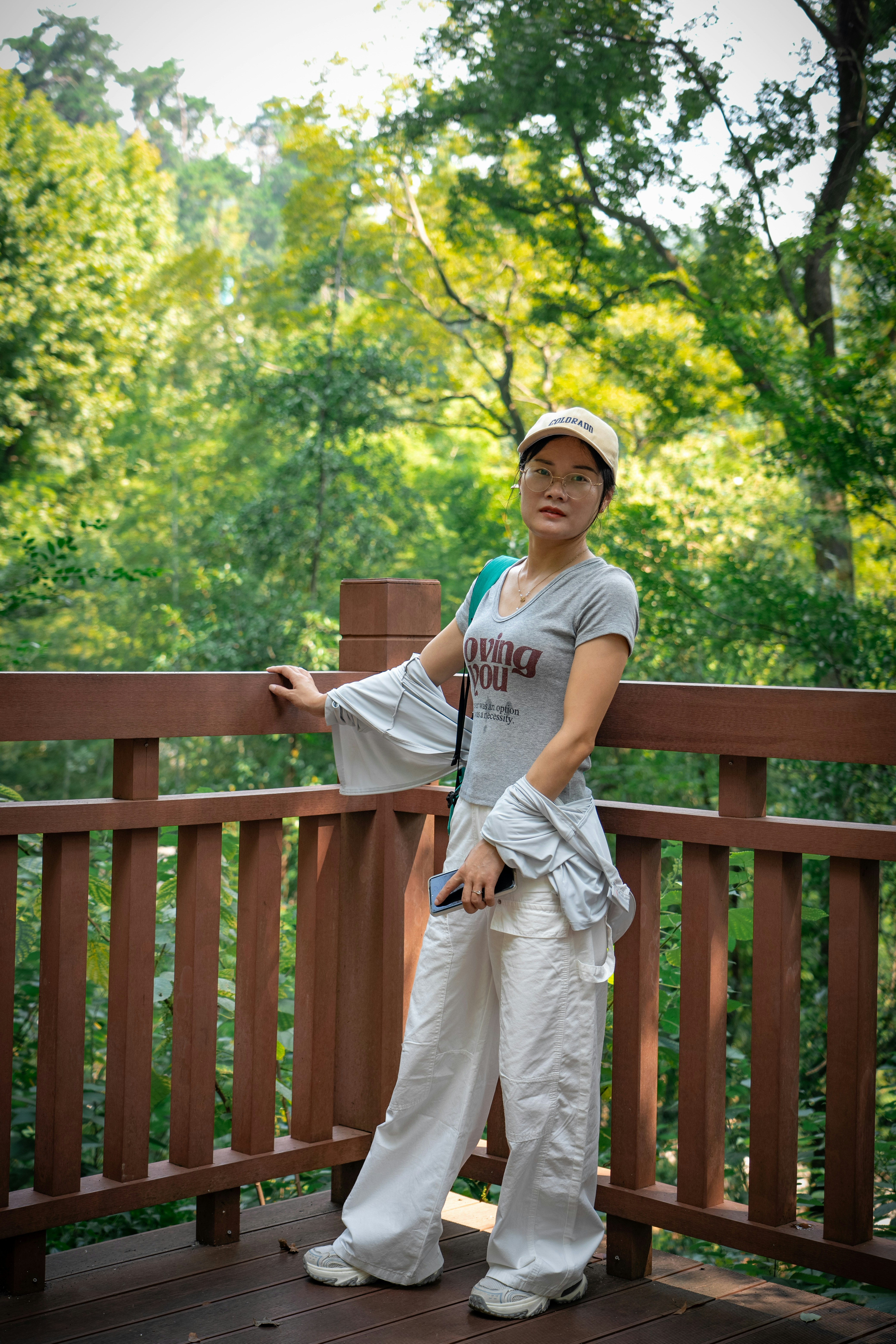 A woman in a grey t-shirt and white pants on a wooden deck