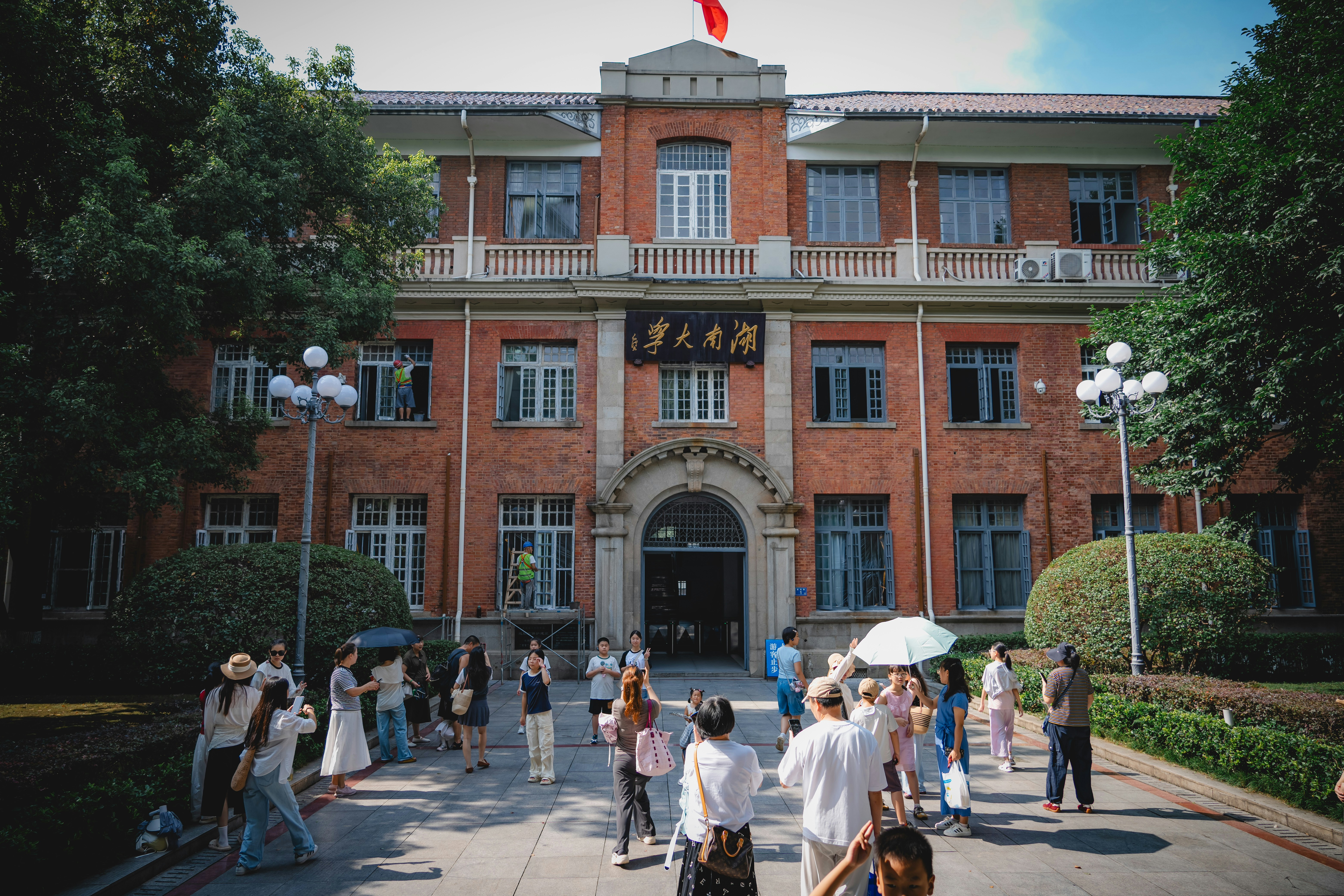 A group of people visiting the historic red brick building of Hunan University