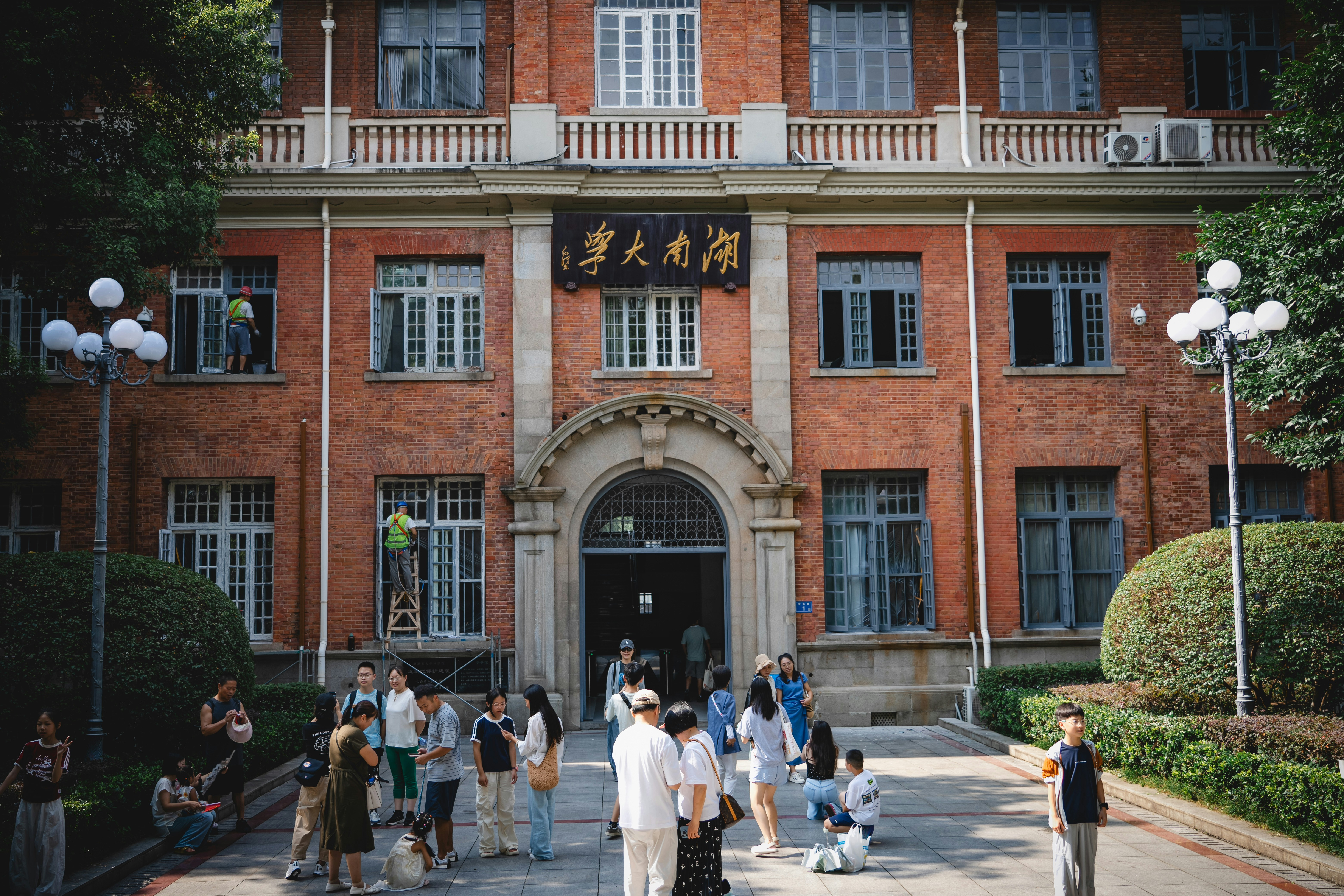 People gathered in front of a historic red brick building with arched entrance