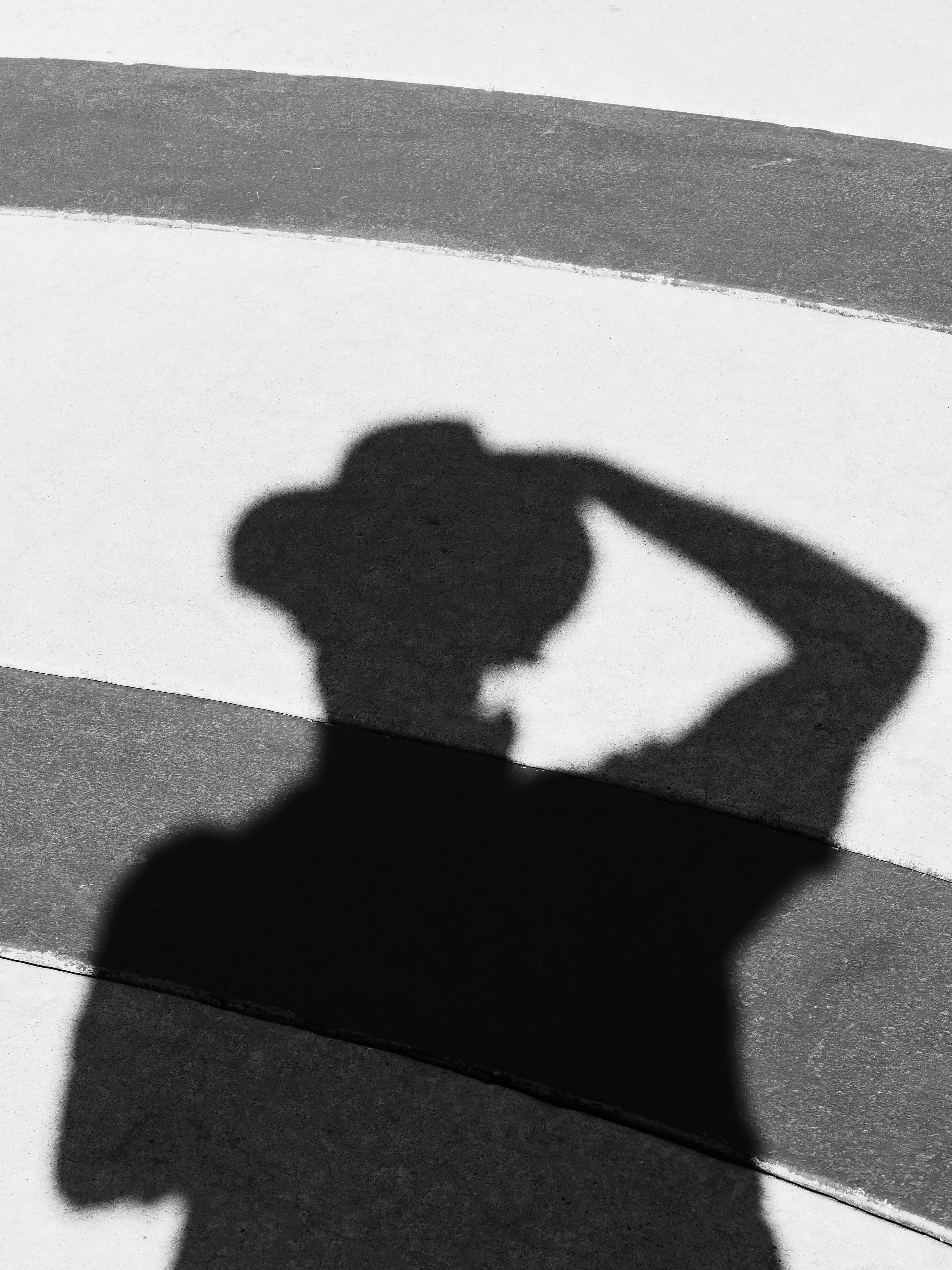 A dark silhouette of a person wearing a hat on a striped surface
