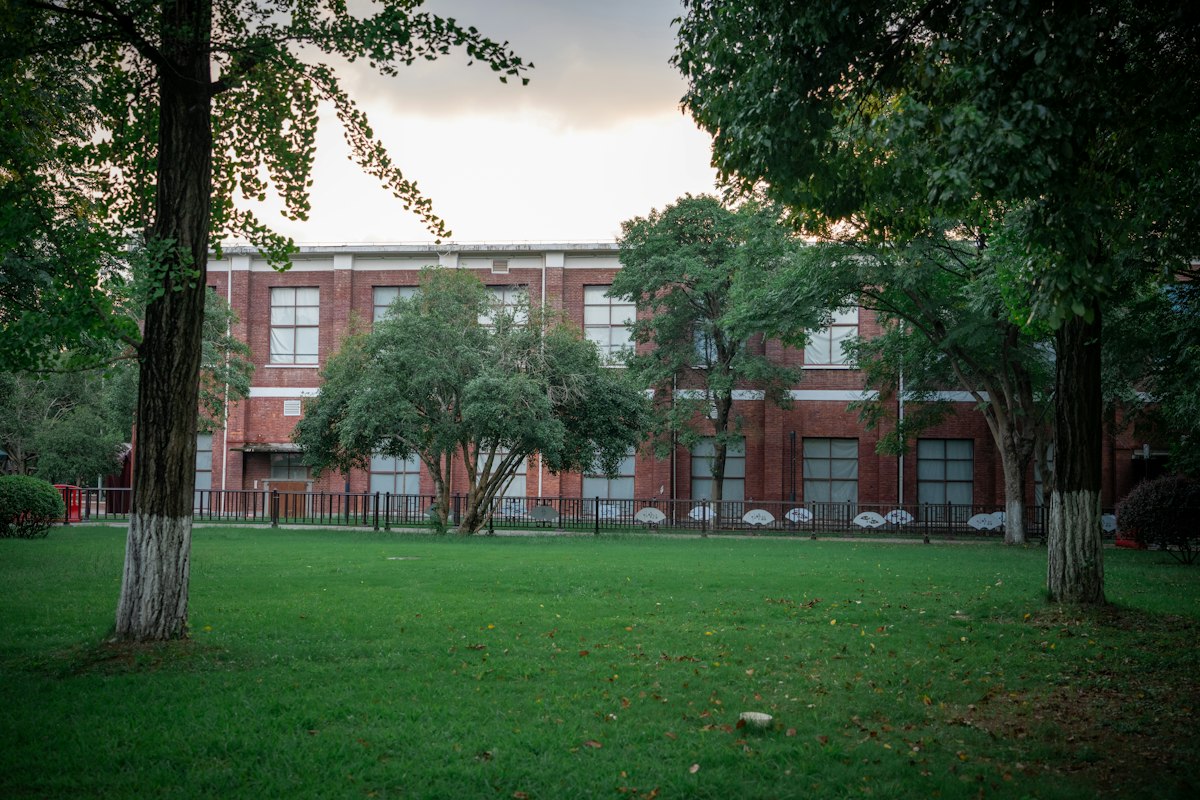 Red brick school building behind a green lawn and trees