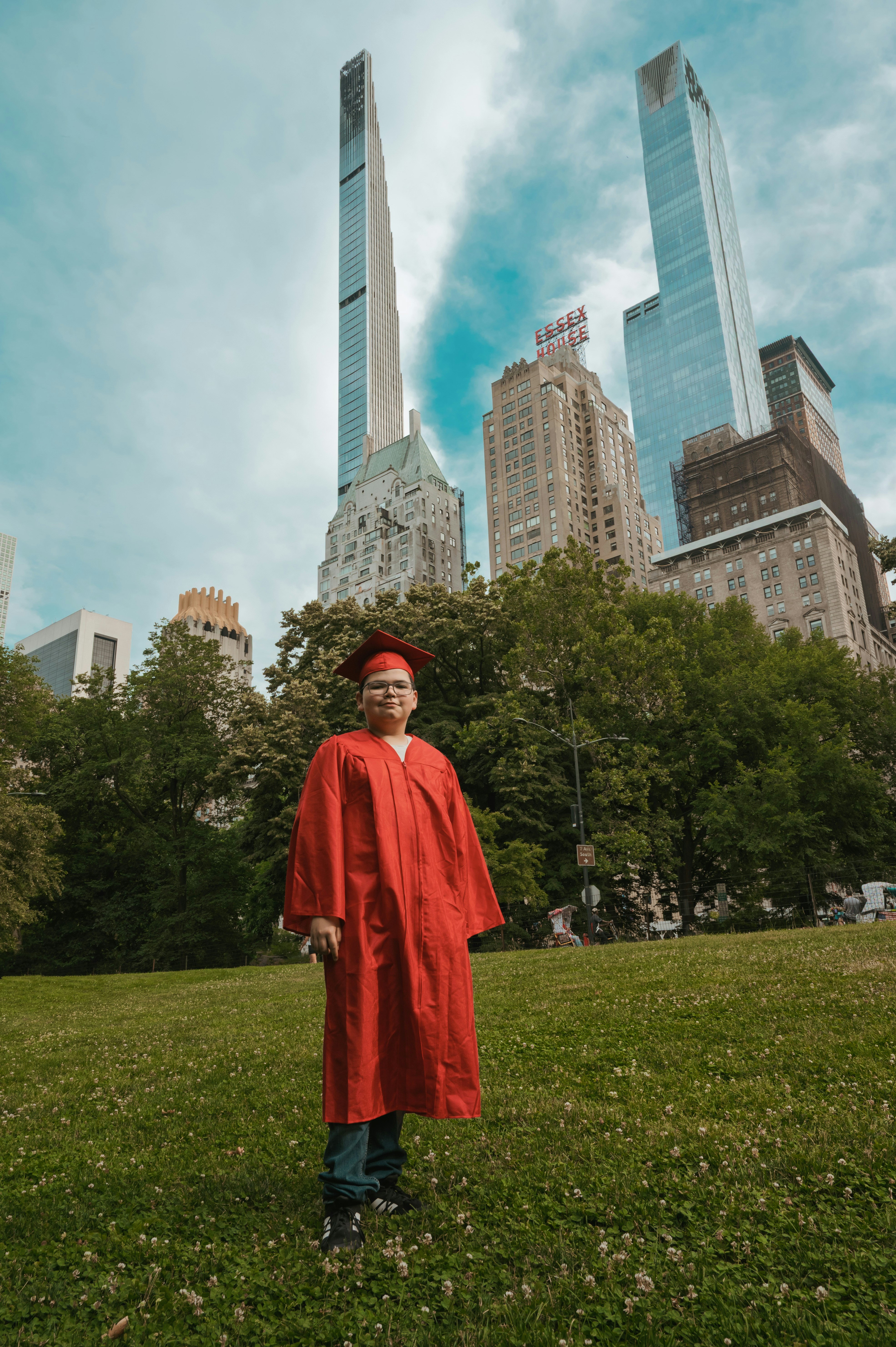 A person in a red graduation gown and cap in Central Park, New York