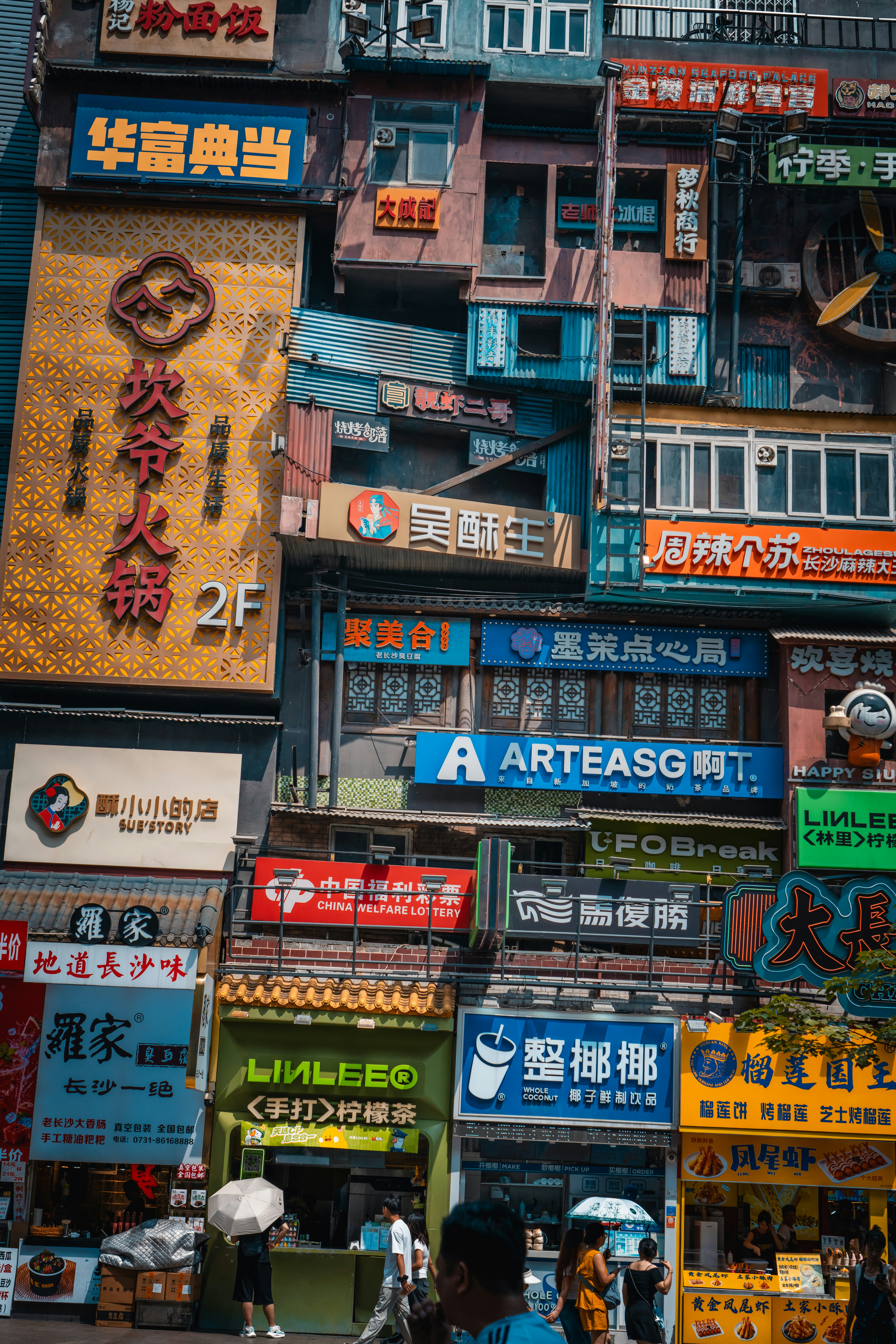 A dense urban street facade covered in colorful neon signs and commercial advertisements