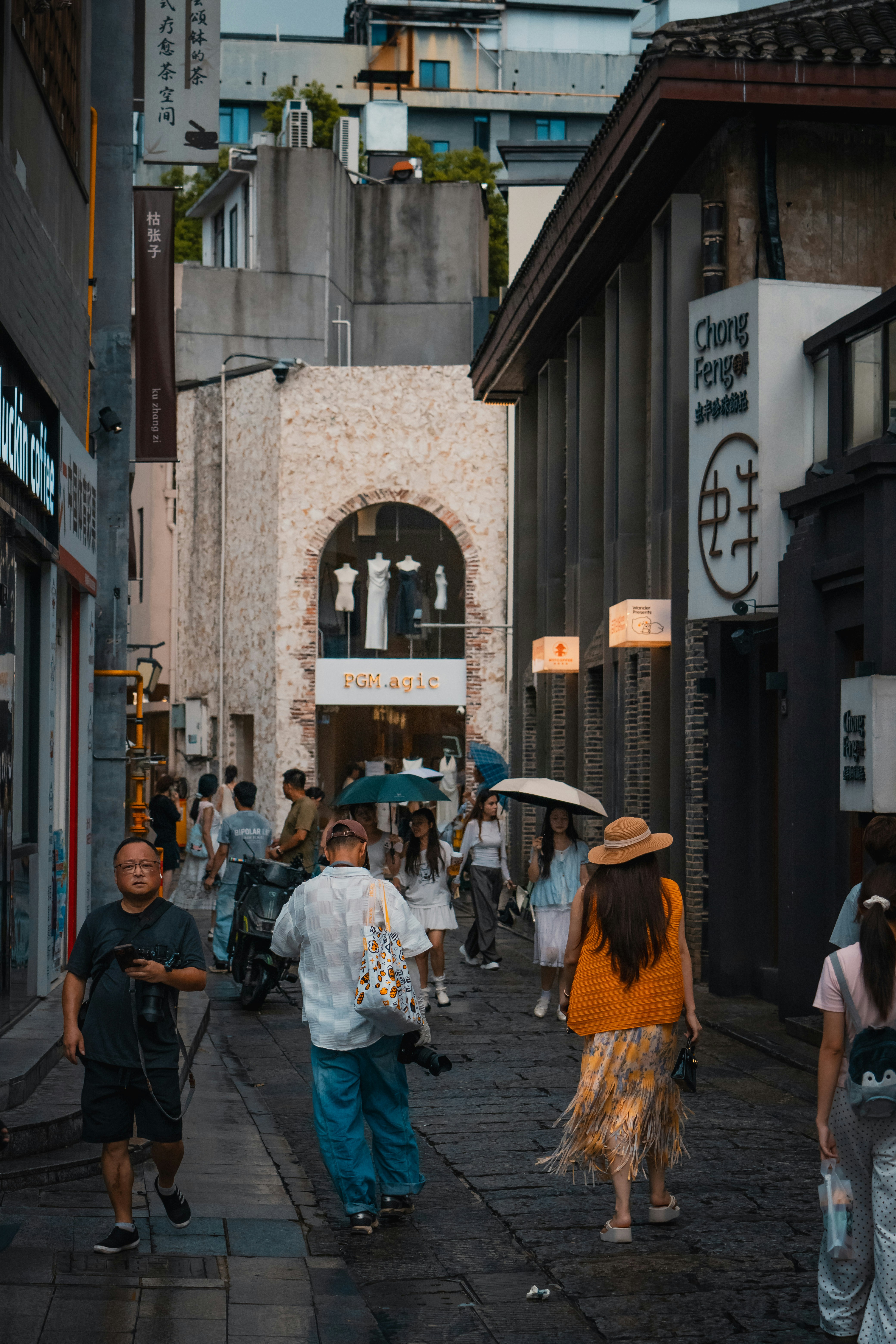 People walking along a narrow stone street lined with shops and cafes