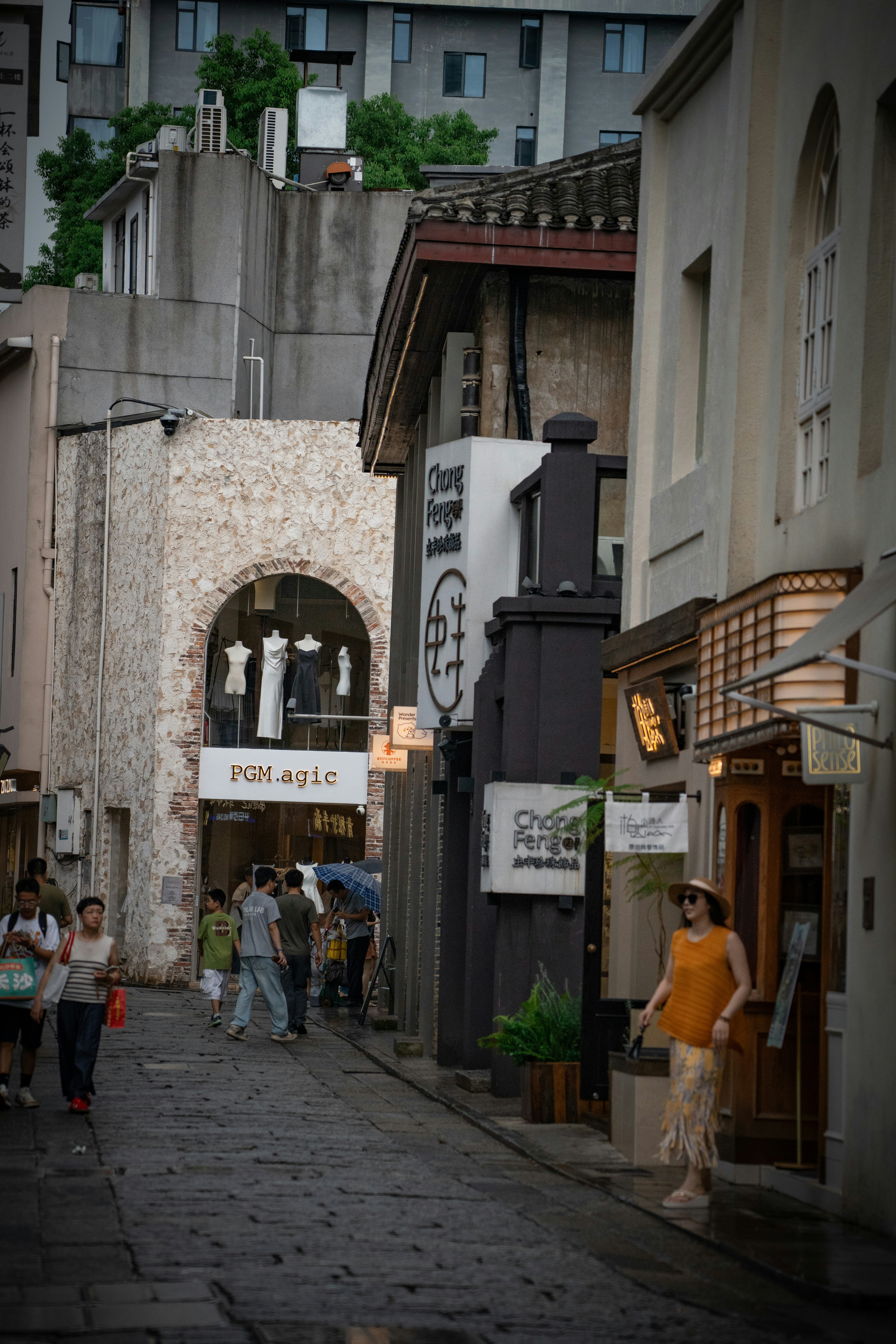 People walking on a stone paved street lined with shops and historic buildings
