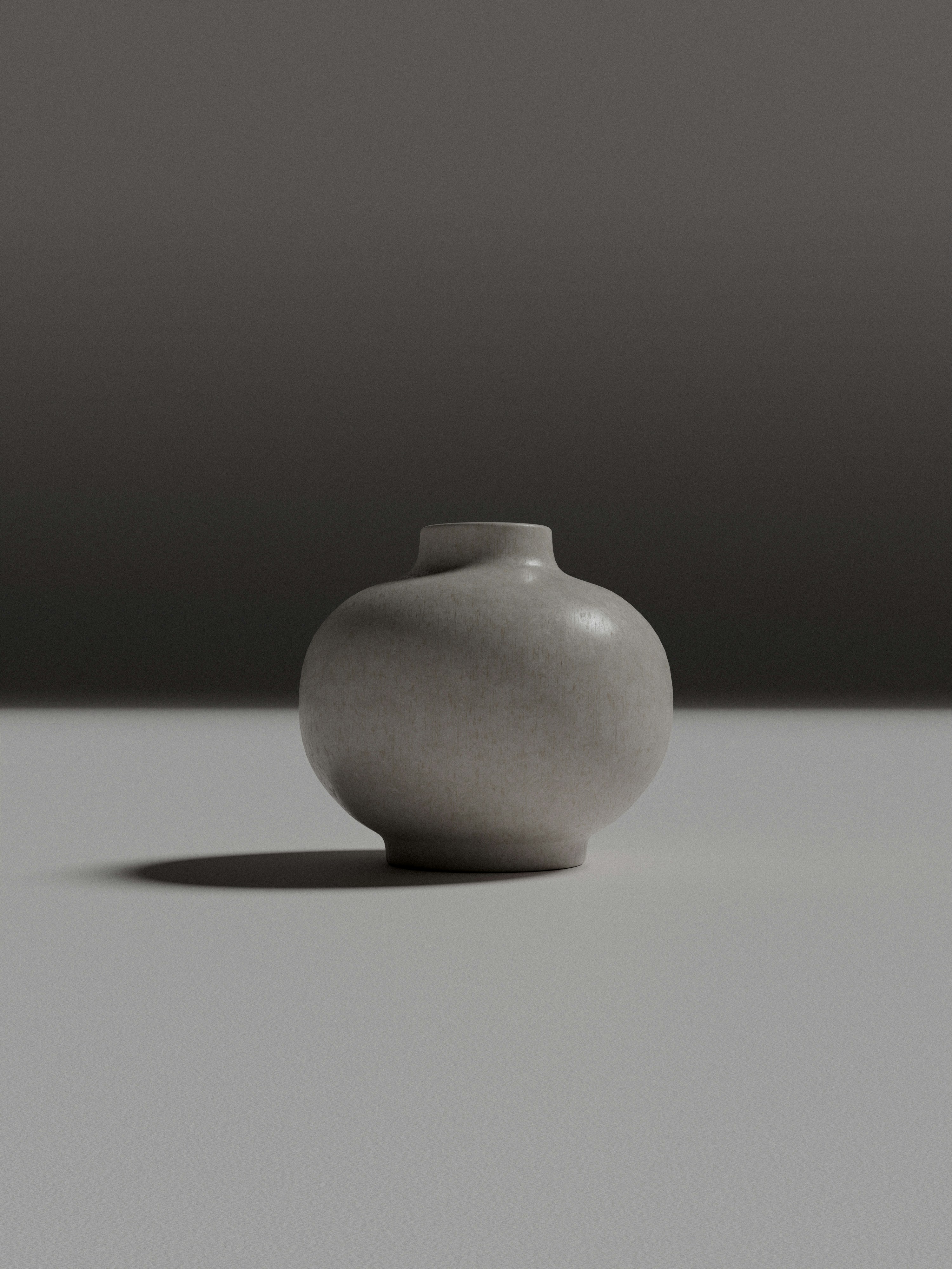 A small grey ceramic vase on a flat surface with a soft shadow